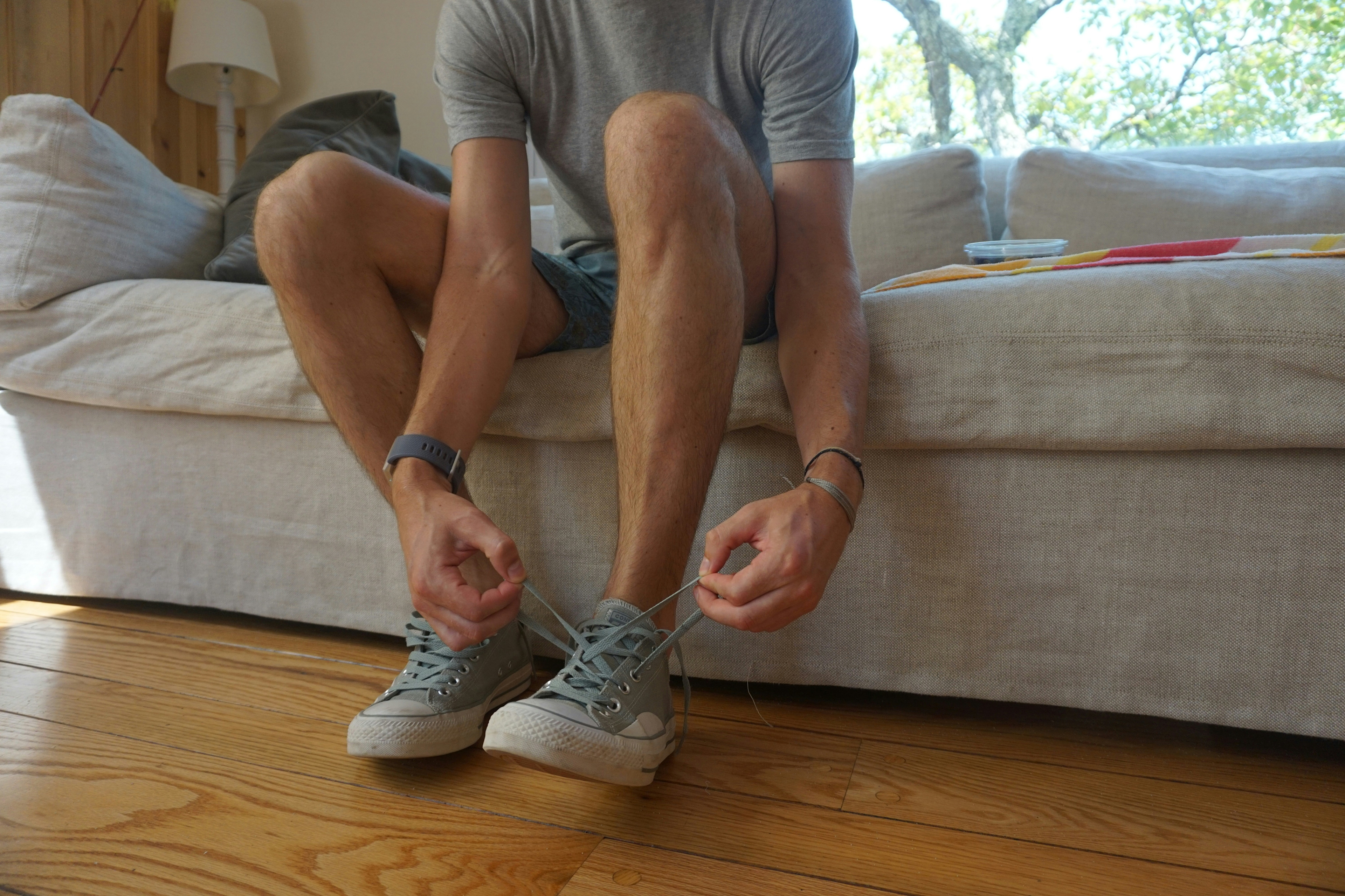 Man laces up sneakers to get ready to work out in home gym.