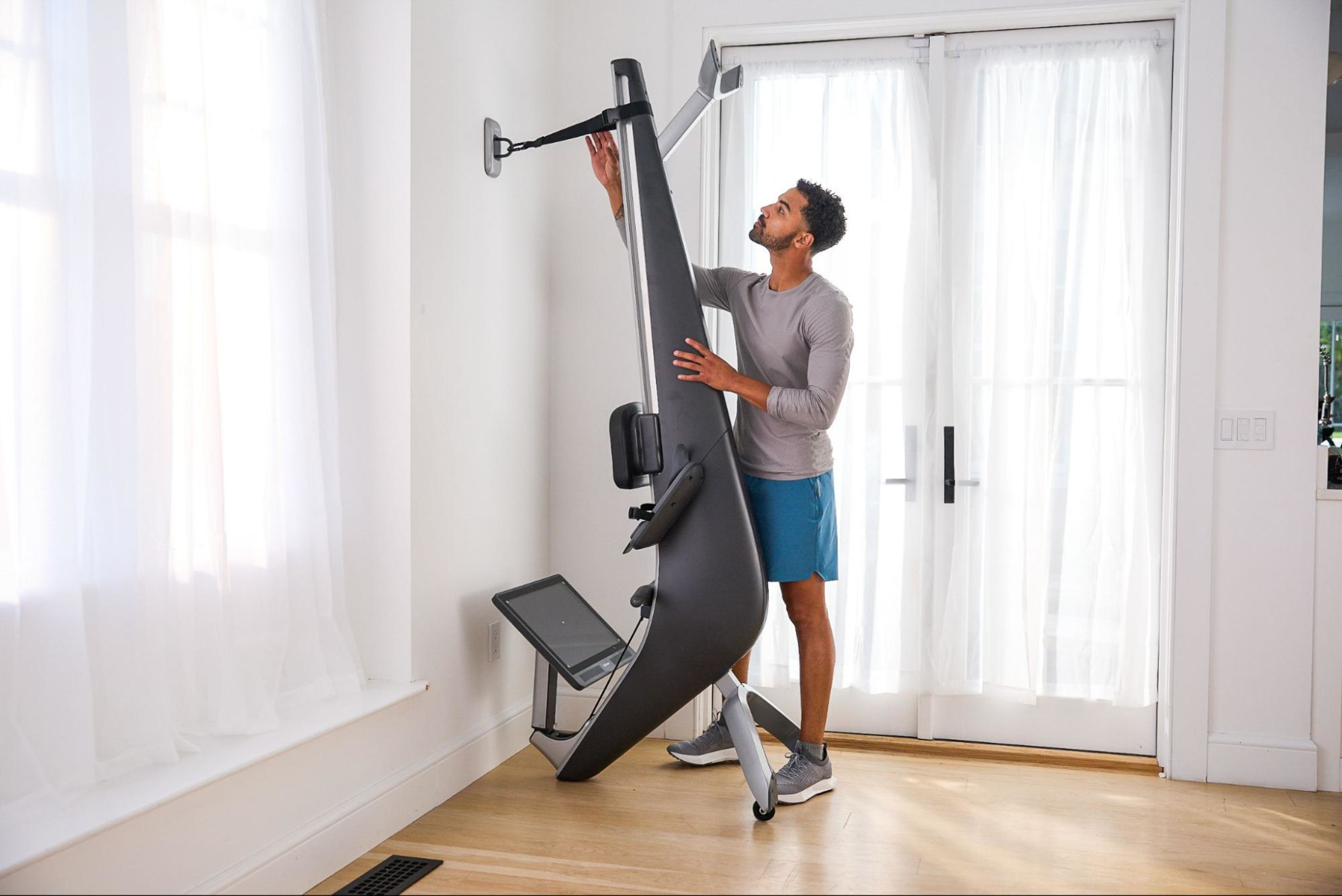 Man uses an upright kit to store his rowing machine vertically.