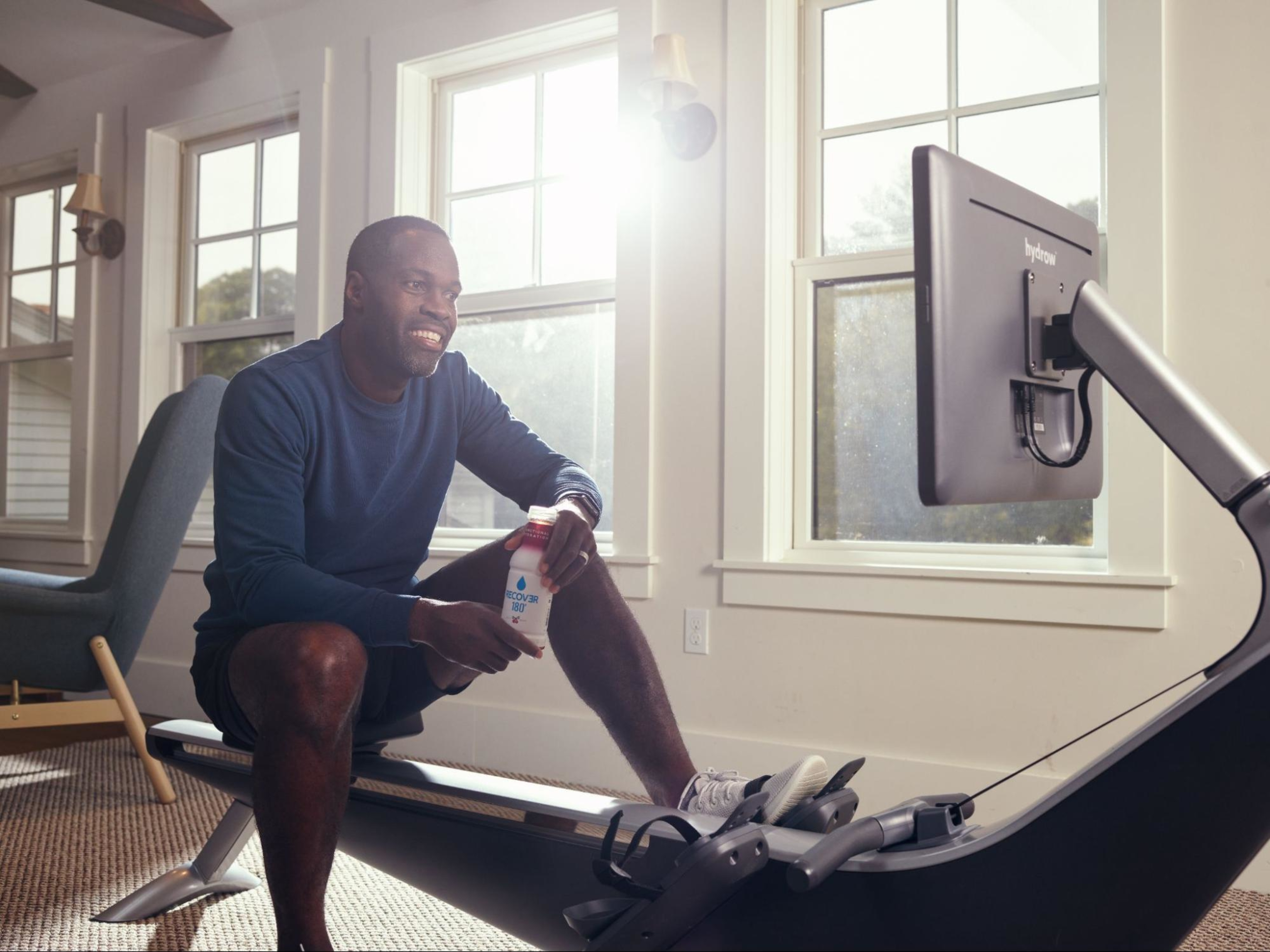 Man works out on a rowing machine on carpet.