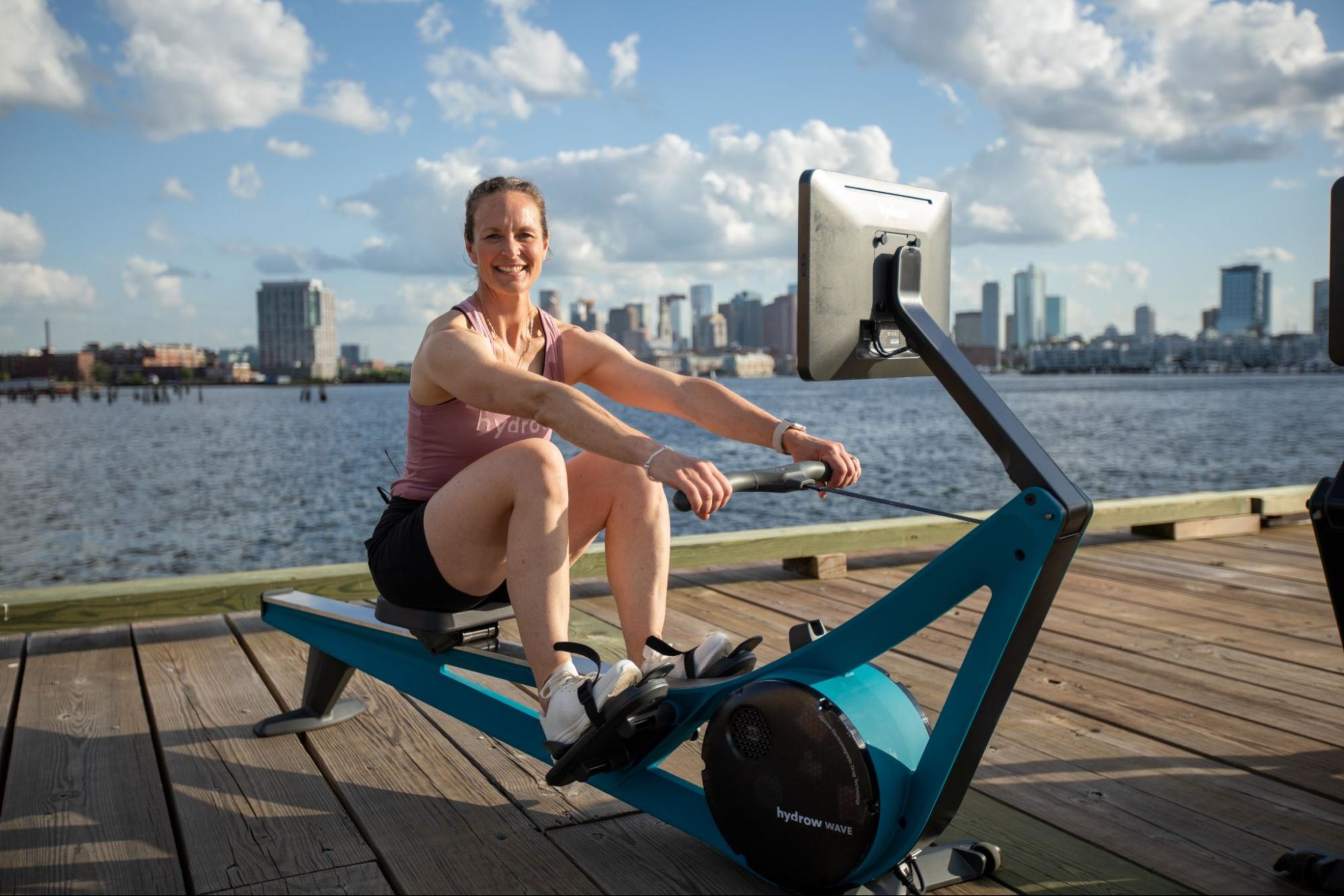 Woman works out on a rowing machine after learning whether it's better to do cardio before or after weights.