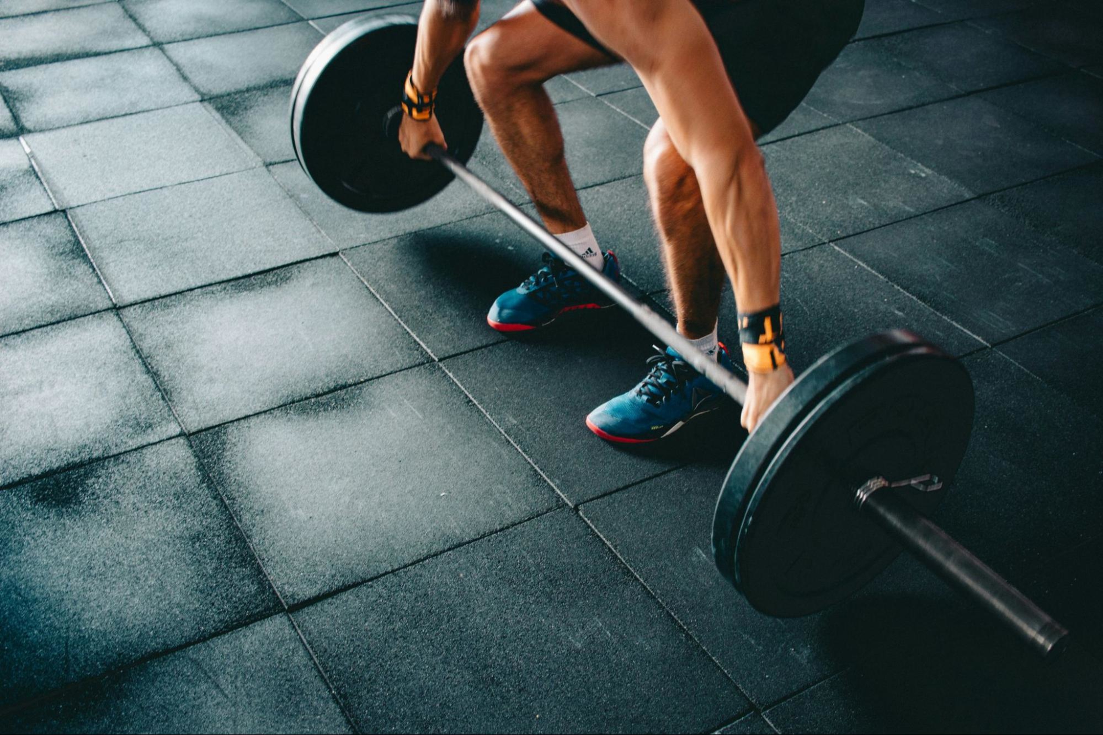 Man does a strength training workout with a large weight after asking "Should I do weights before cardio?"