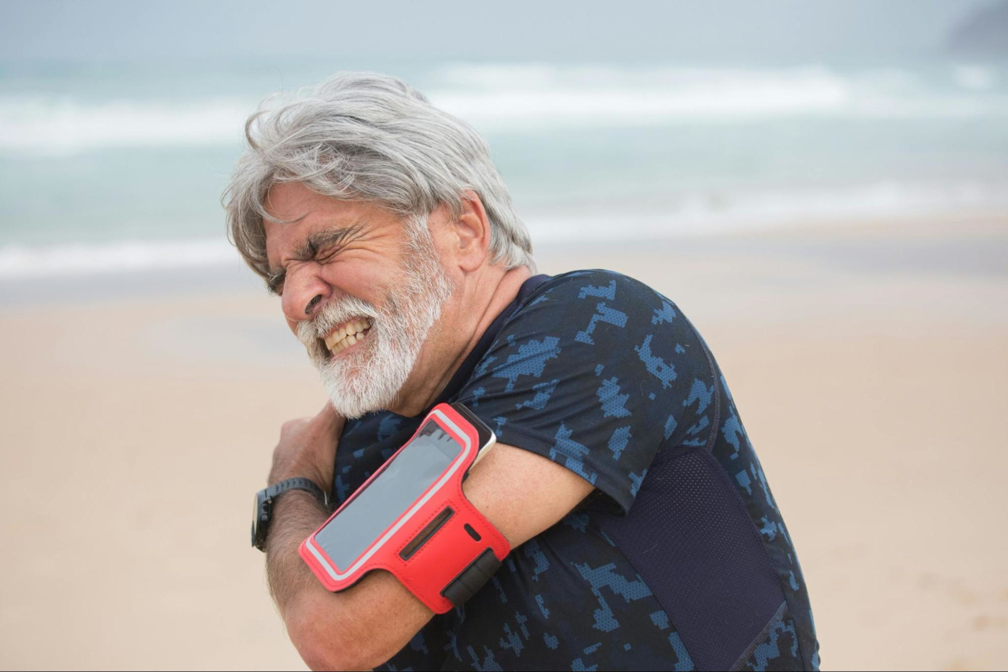 Man holds his shoulder as he experiences a rotator cuff injury, a common exercise injury.