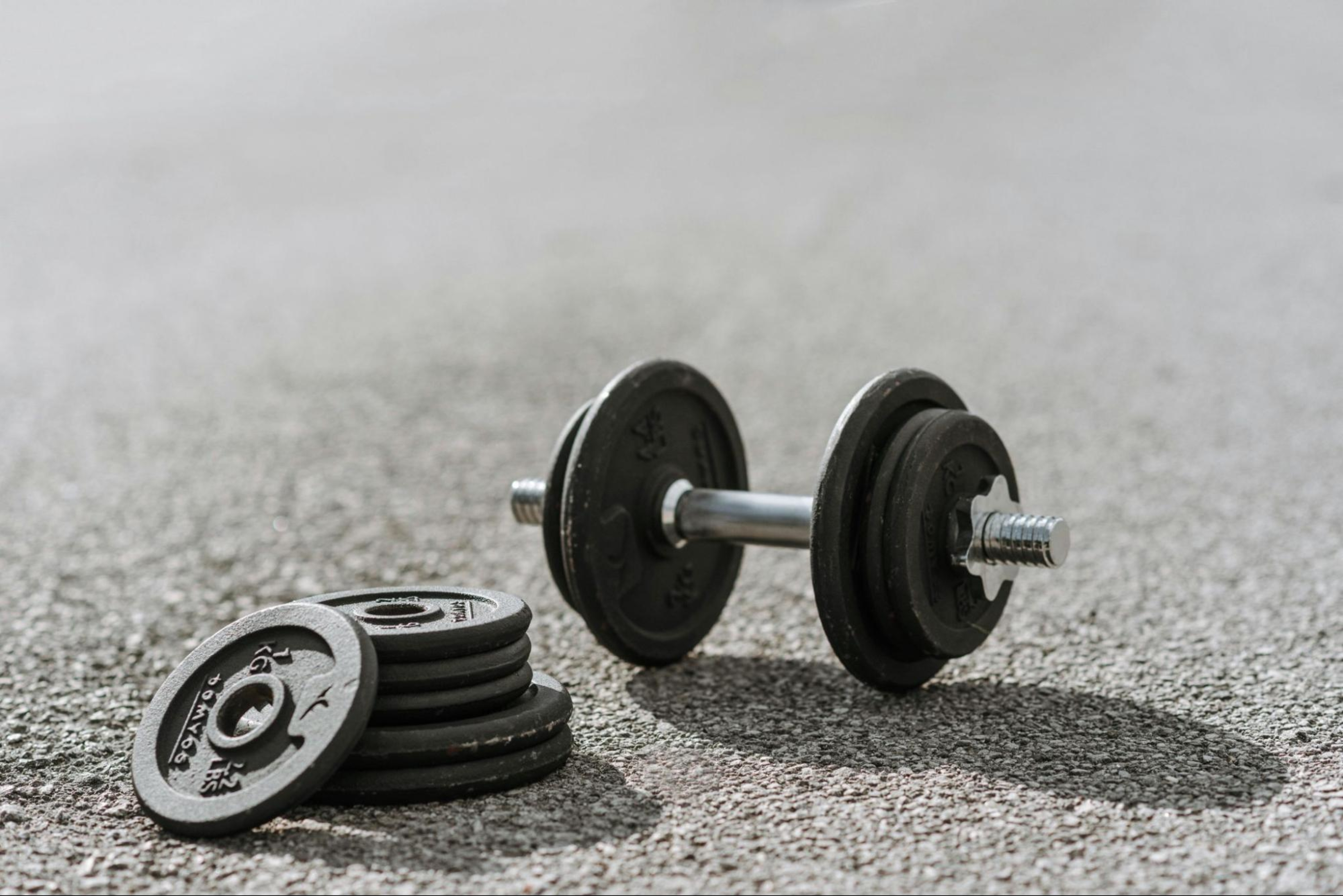 Adjustable dumbbell and weights on the pavement.