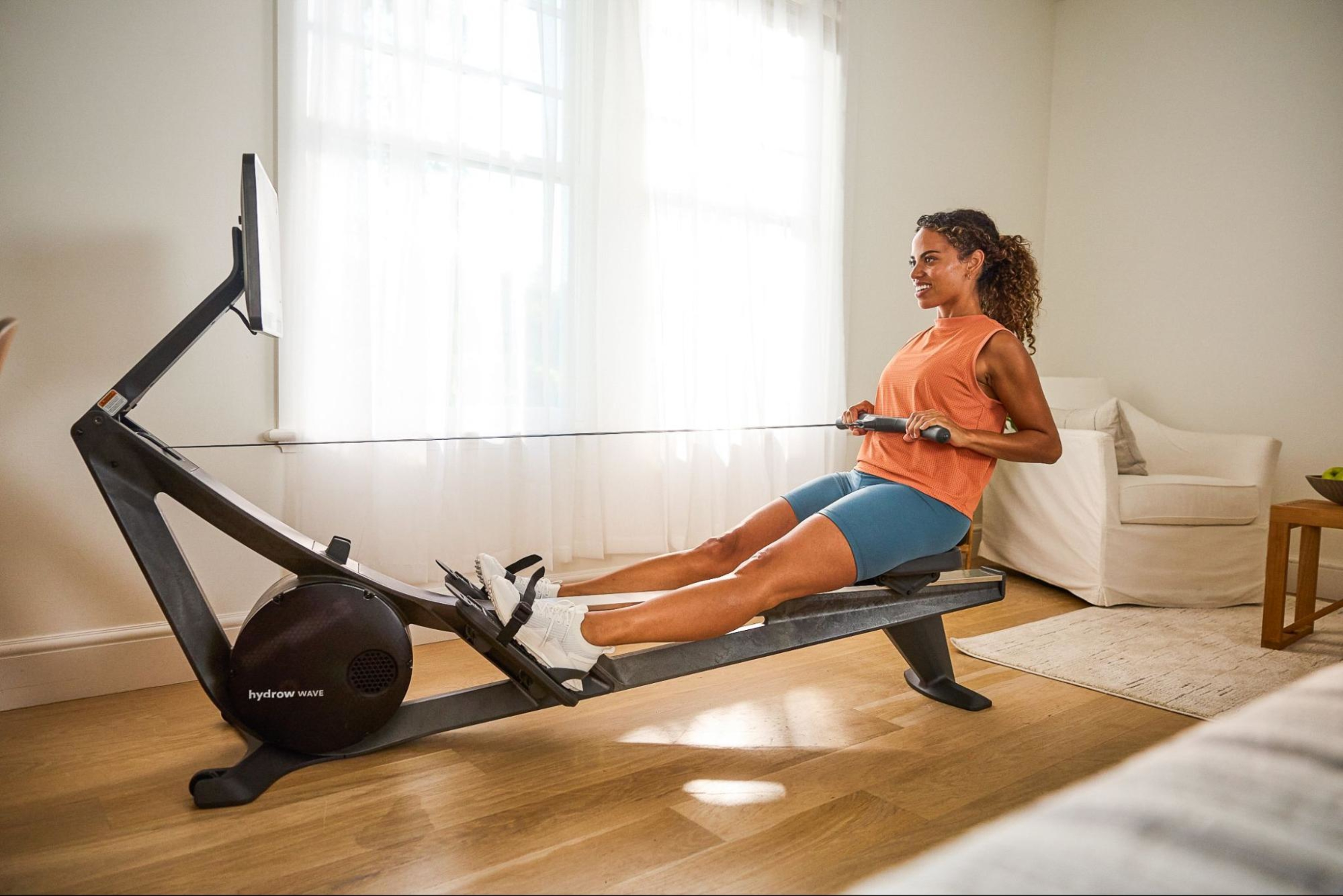 Woman does a quick rowing machine workout, which is popular among people with kids for its efficiency.