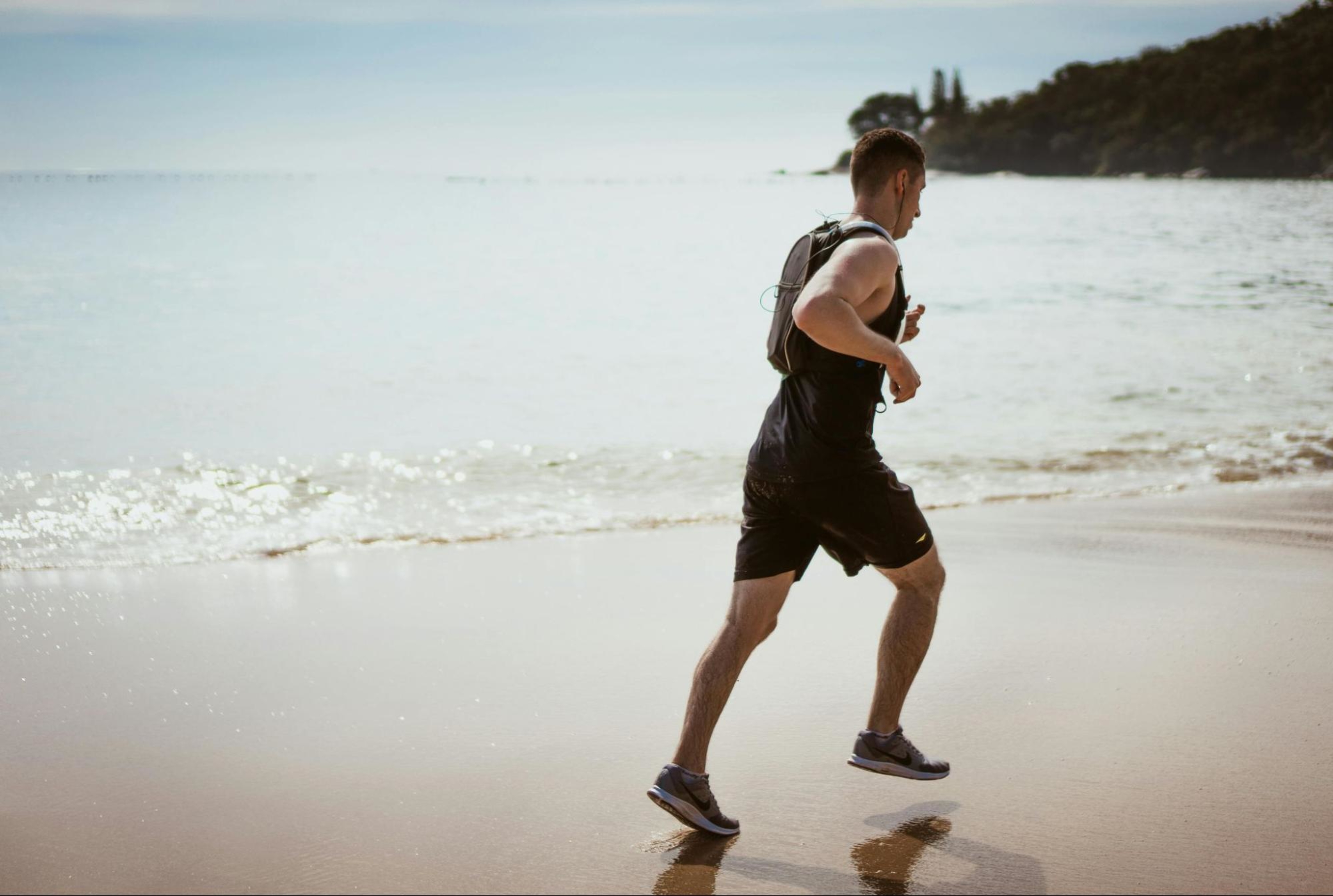 Man runs on the beach to demonstrate exercise.