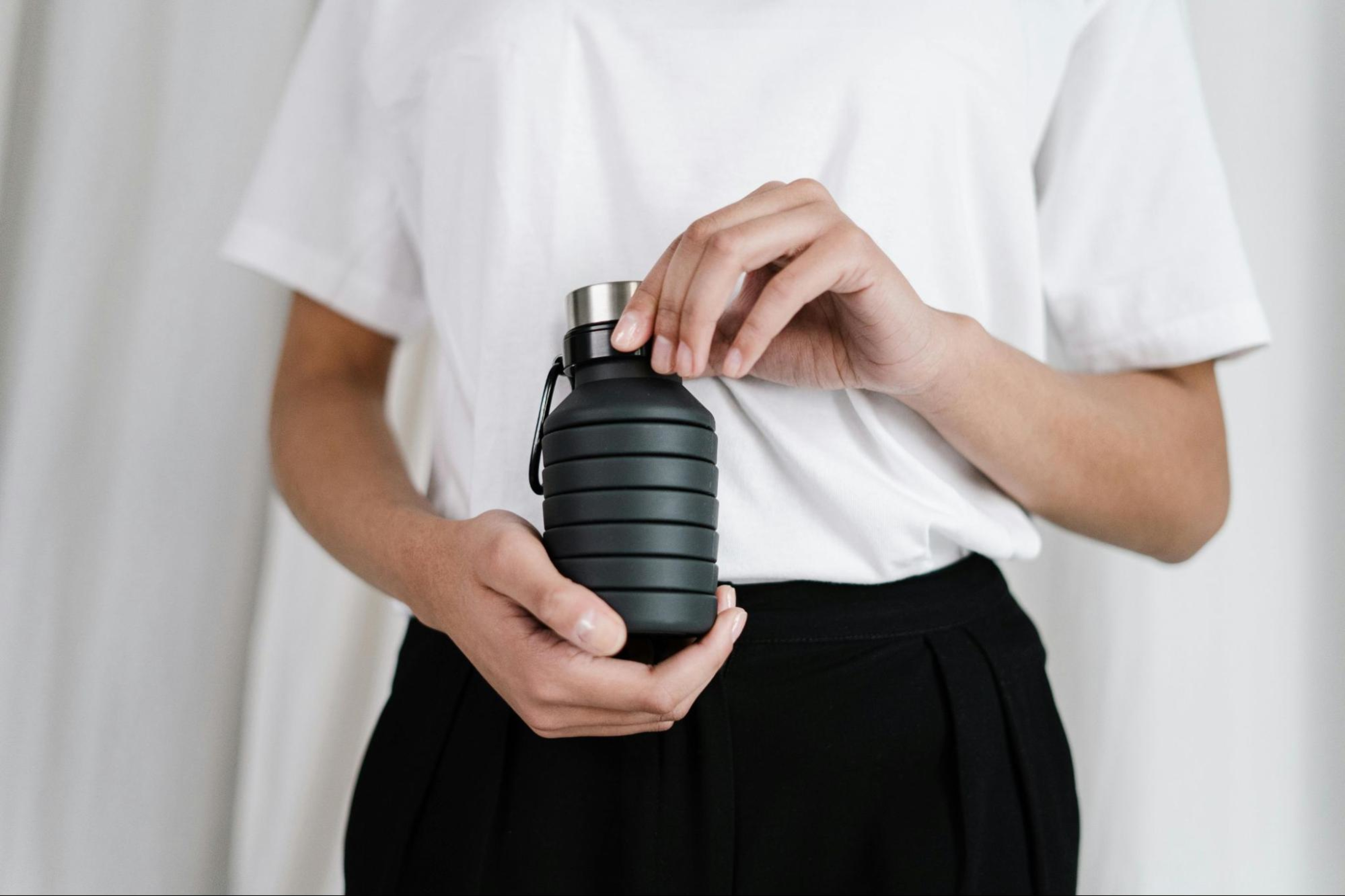 Woman holds a reusable water bottle, an example of more sustainable fitness.