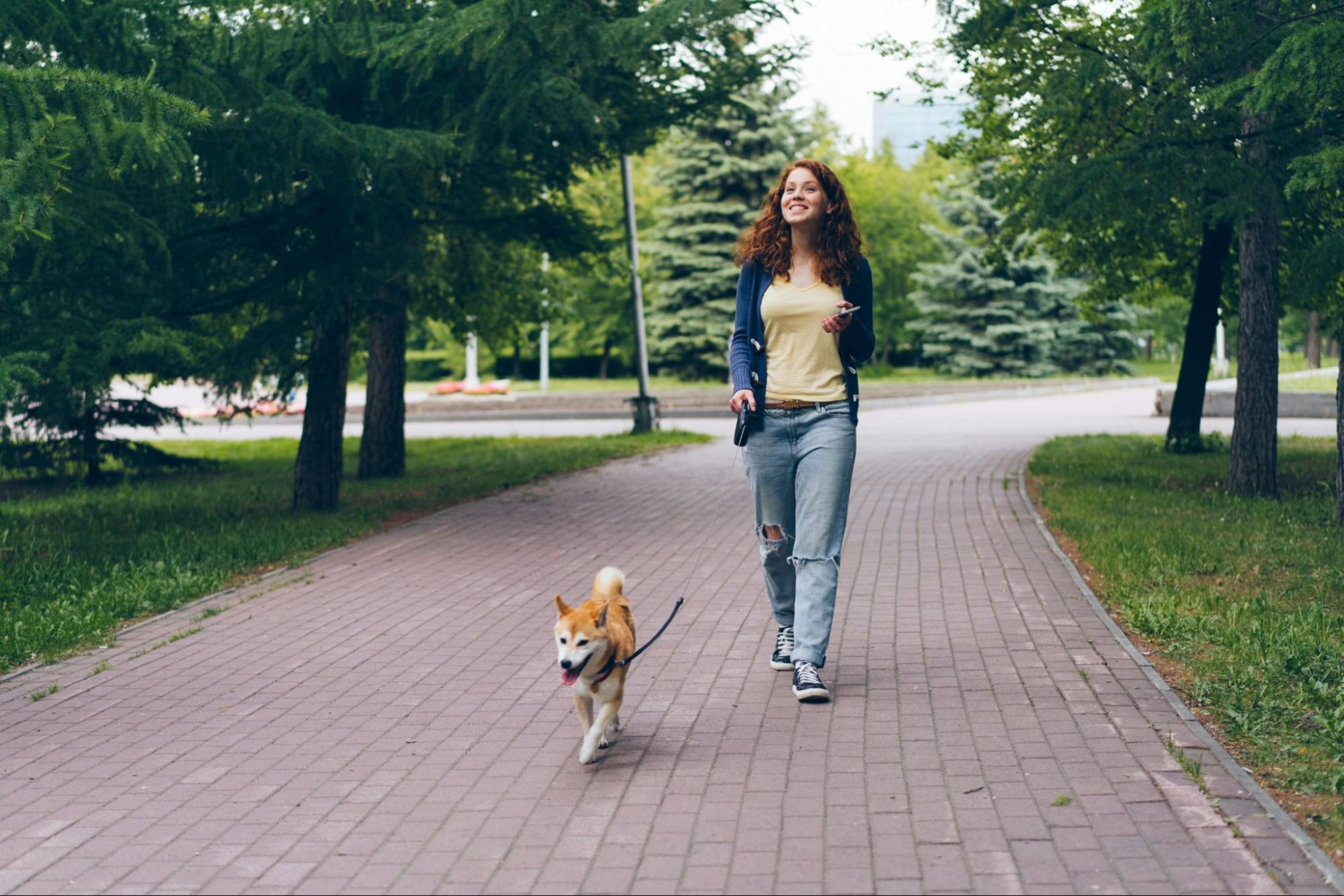 Woman embraces gentle fitness trend by going on a walk with her dog.