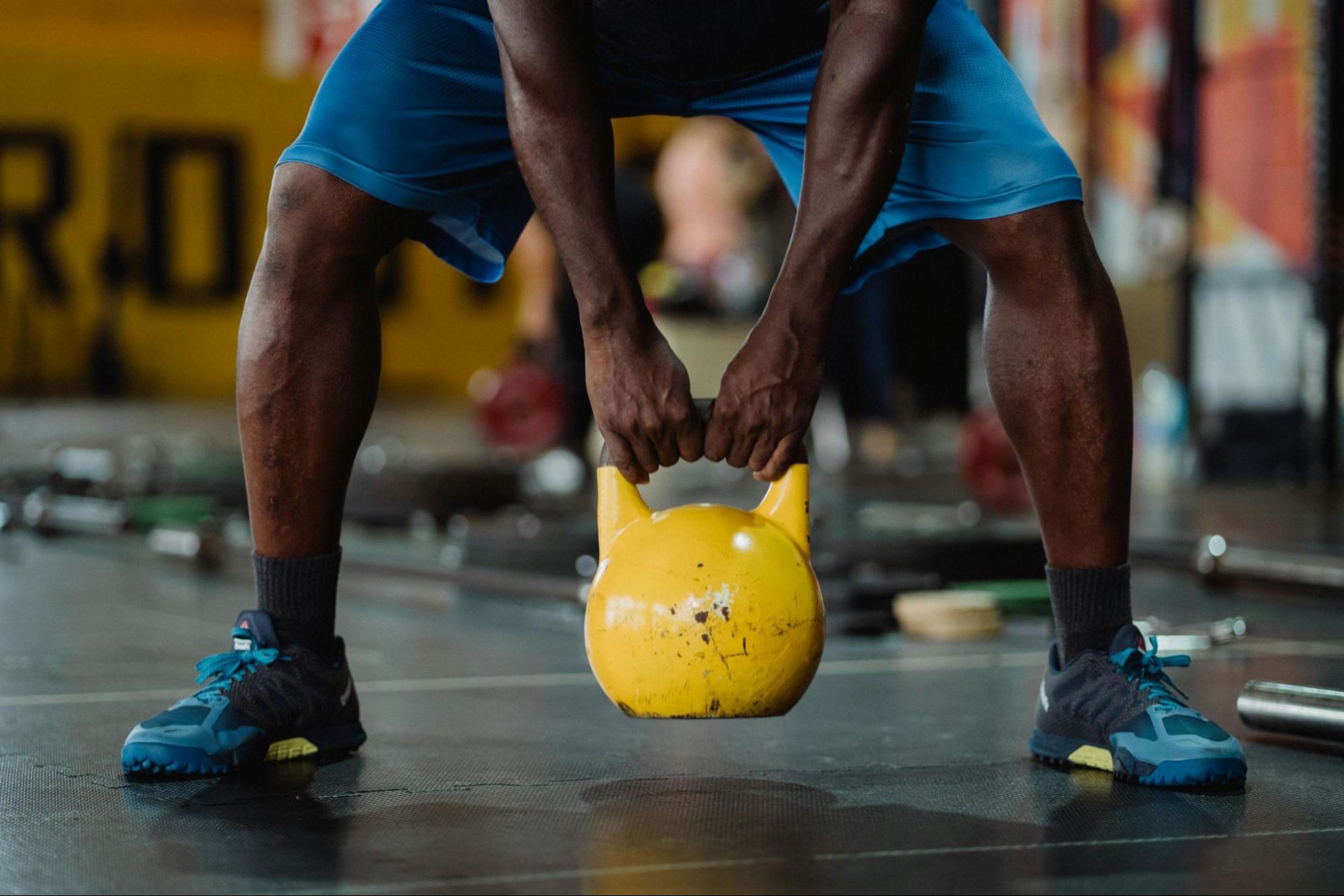 Man does a functional strength training workout with a kettlebell in a gym.