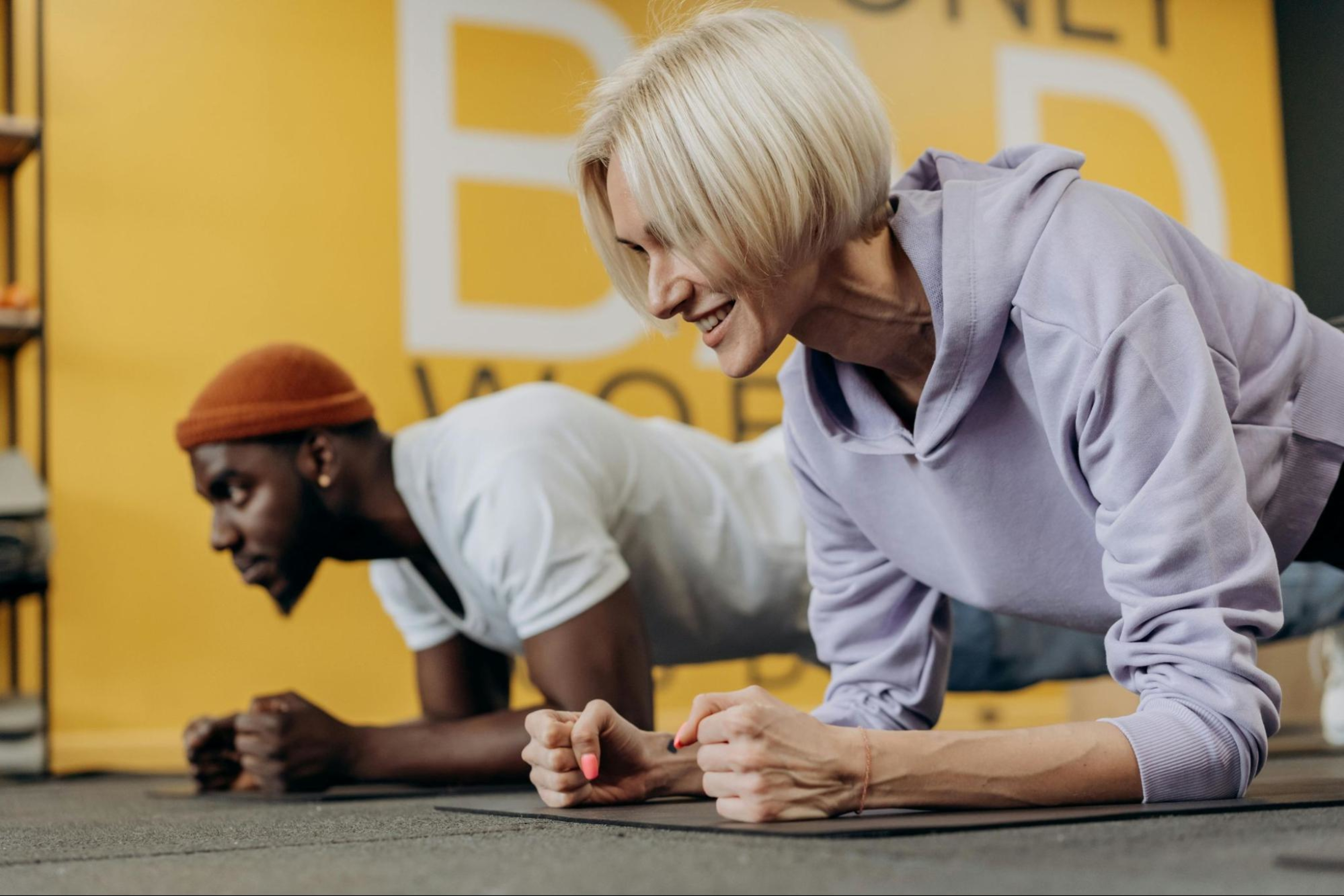 Man and woman do planks as they work out at the gym.