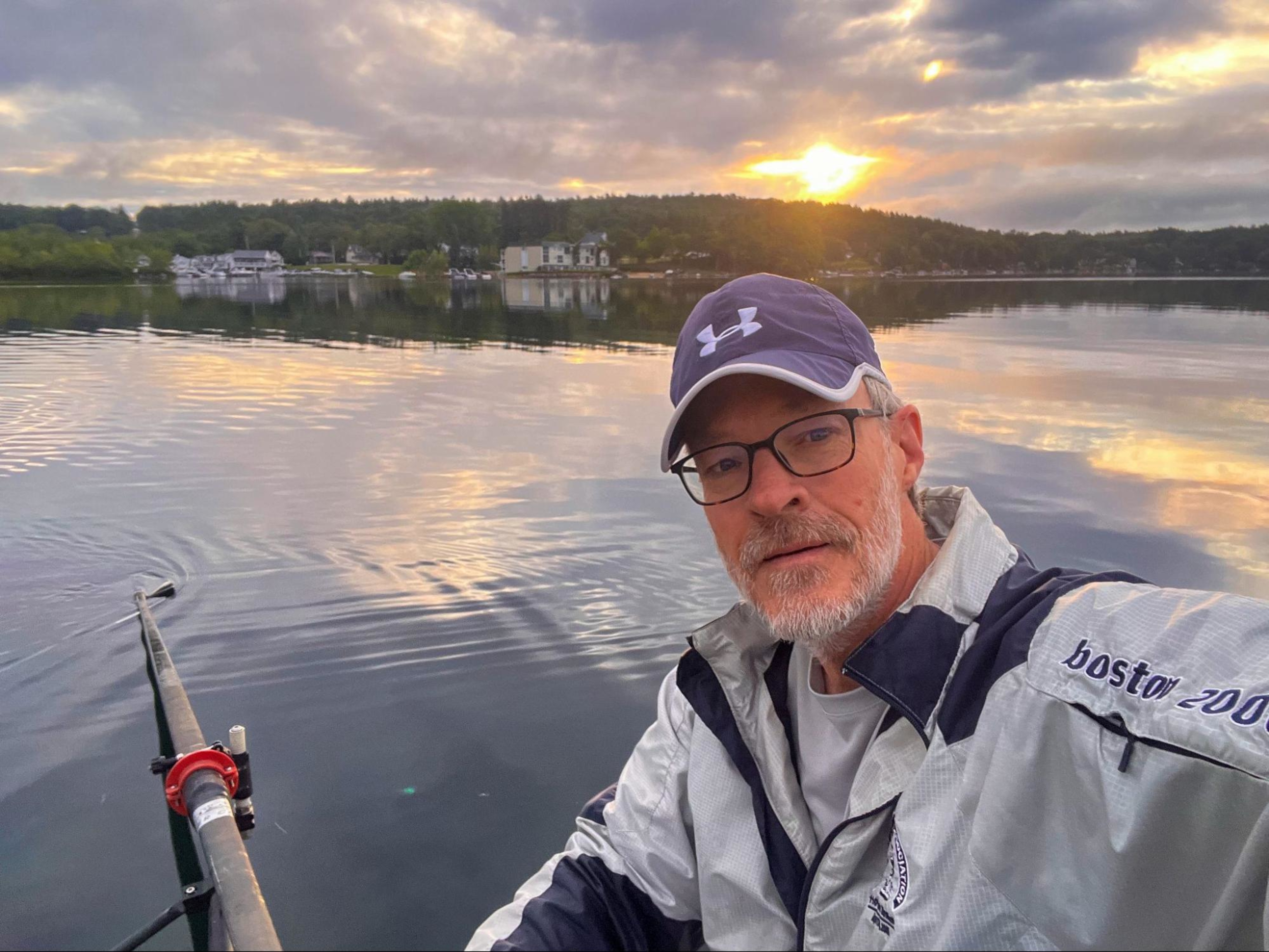 Hydrow member Bob Manley rows outdoors on a lake.