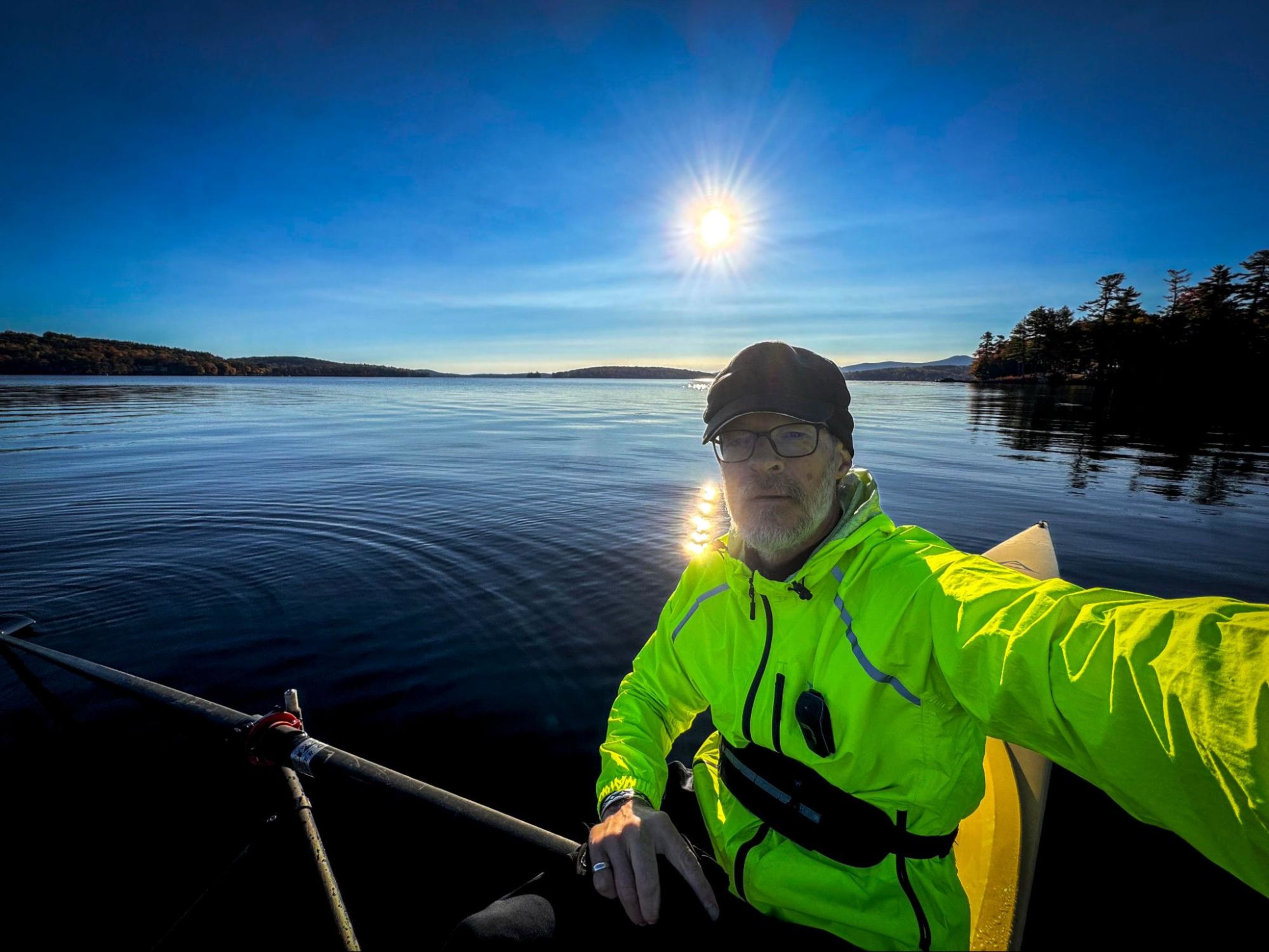 Hydrow member Bob Manley rows outdoors on a lake.