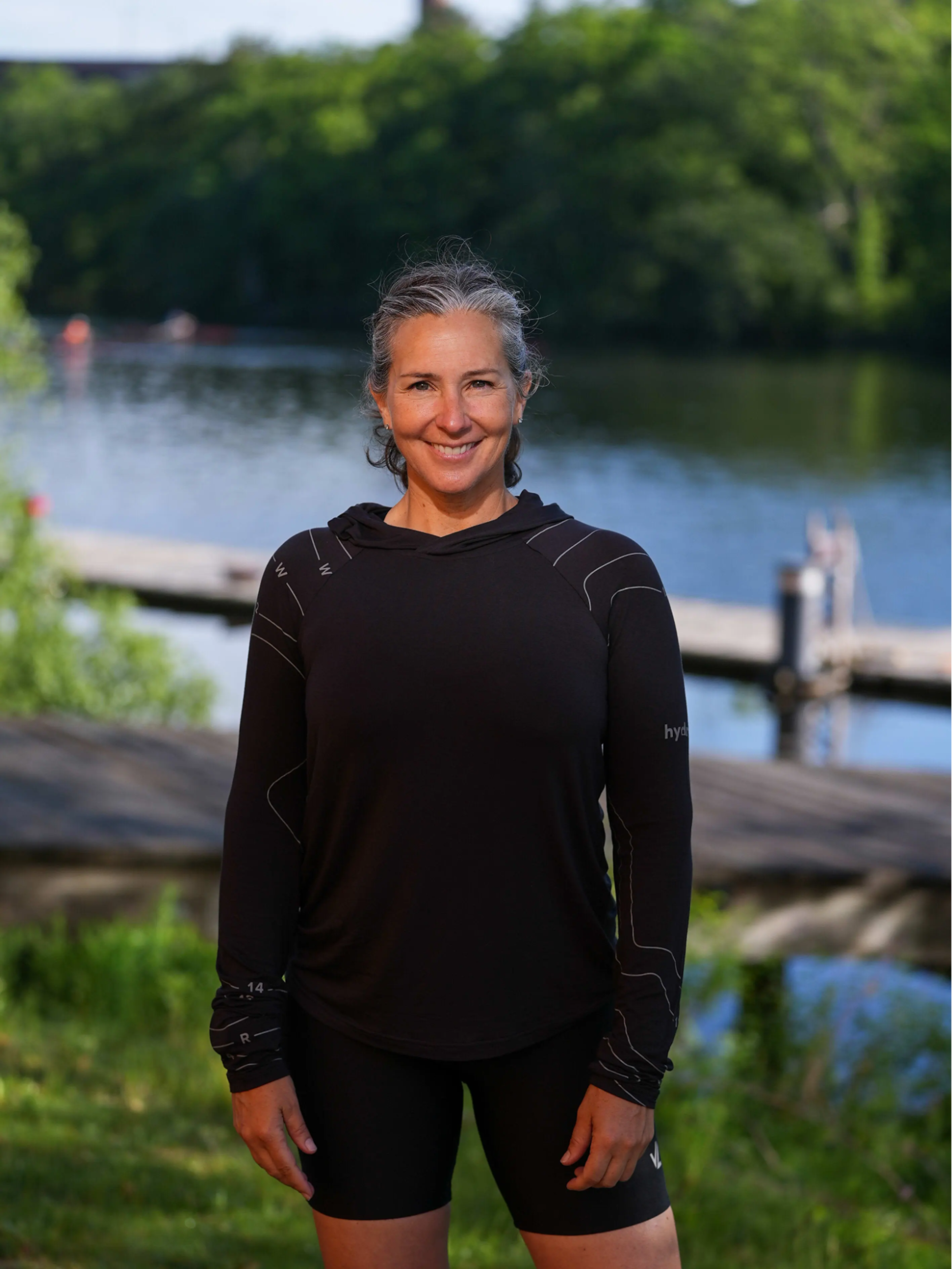 Megan Hanewald, Hydrow's personal coach, stands in front of a body of water.
