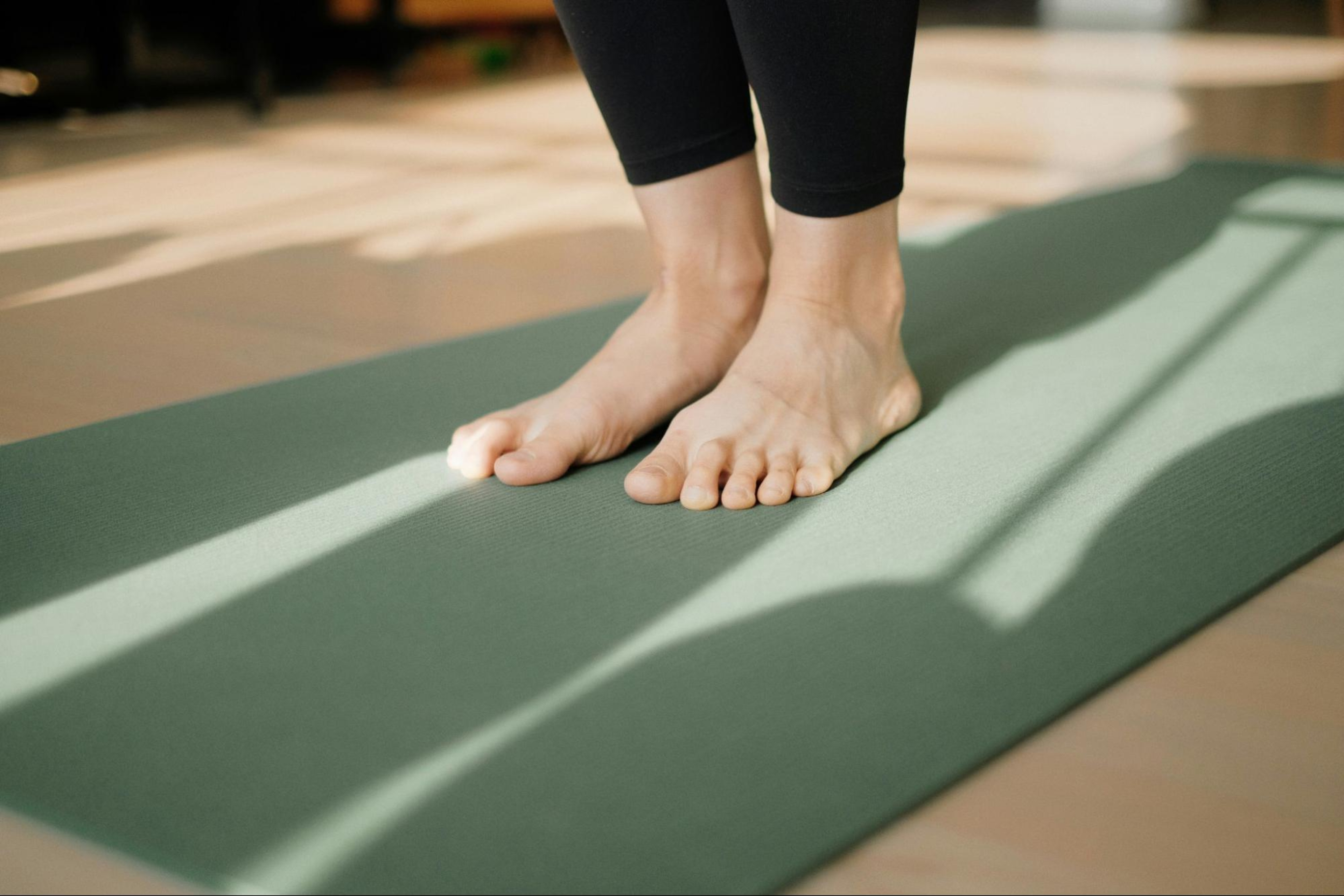 Woman stands on a green yoga mat after learning whether Pilates counts as strength training.