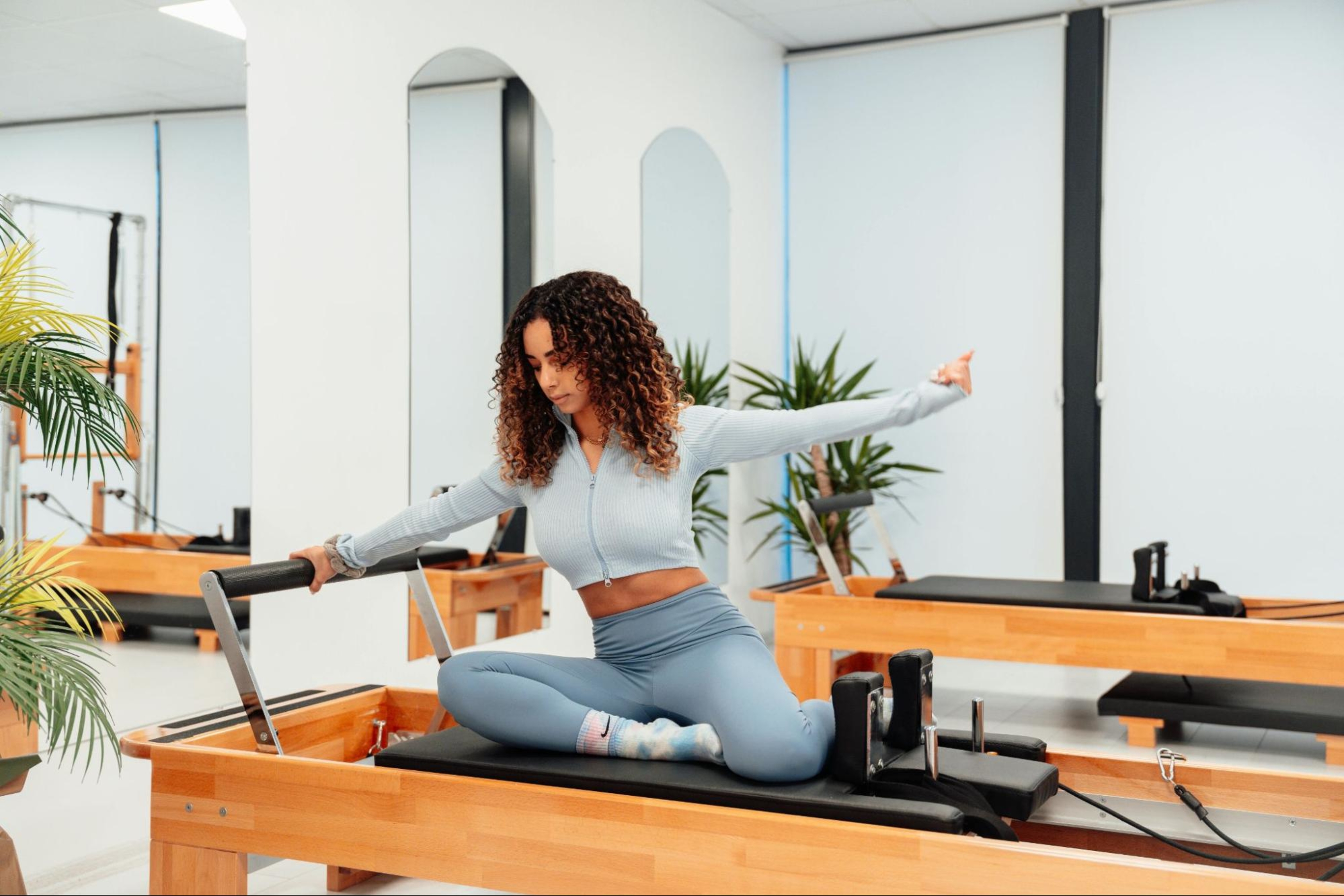 Woman does a Pilates workout on a Reformer machine after learning whether Pilates is cardio or strength training.