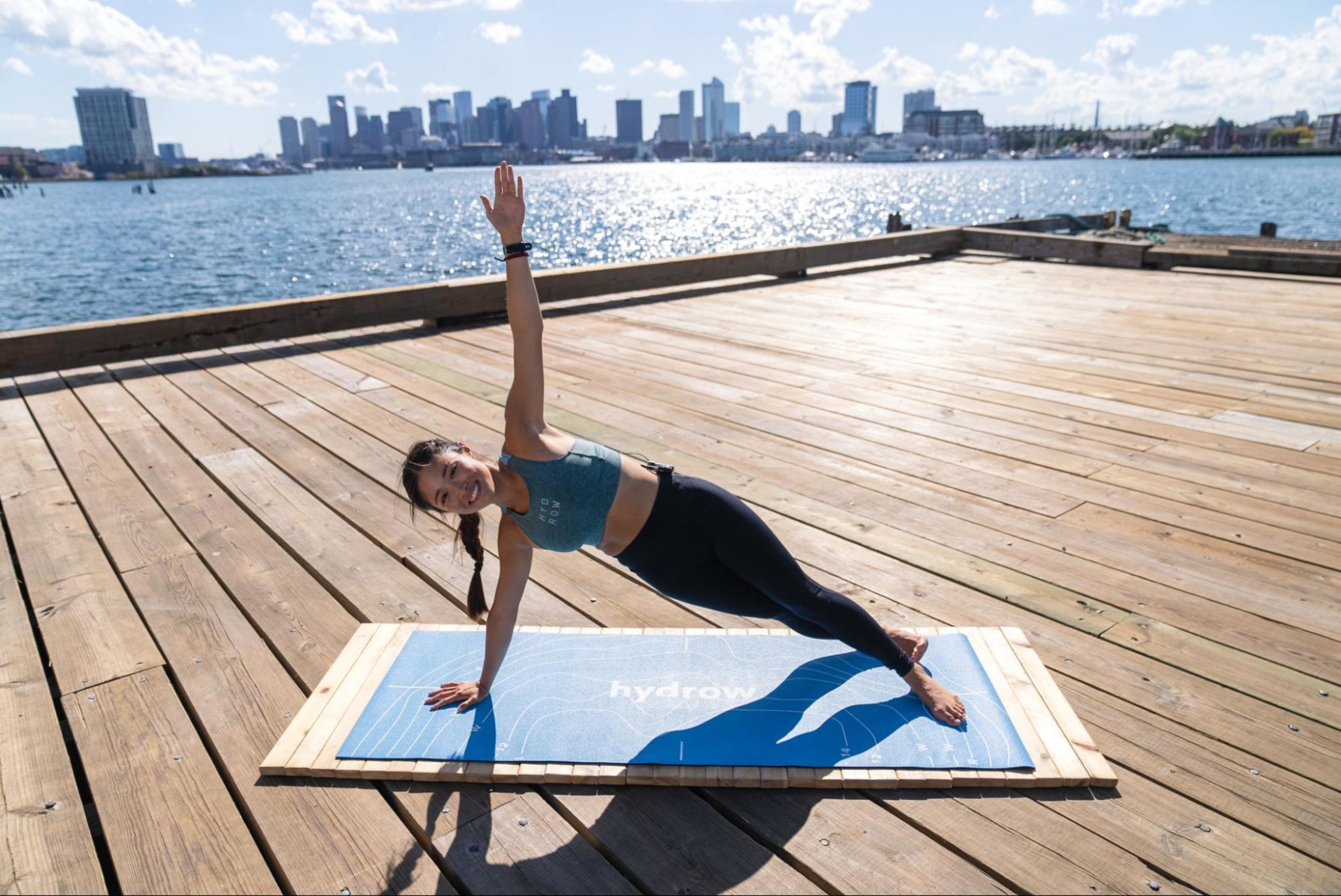 Woman does Pilates for strength training outdoors by the water.