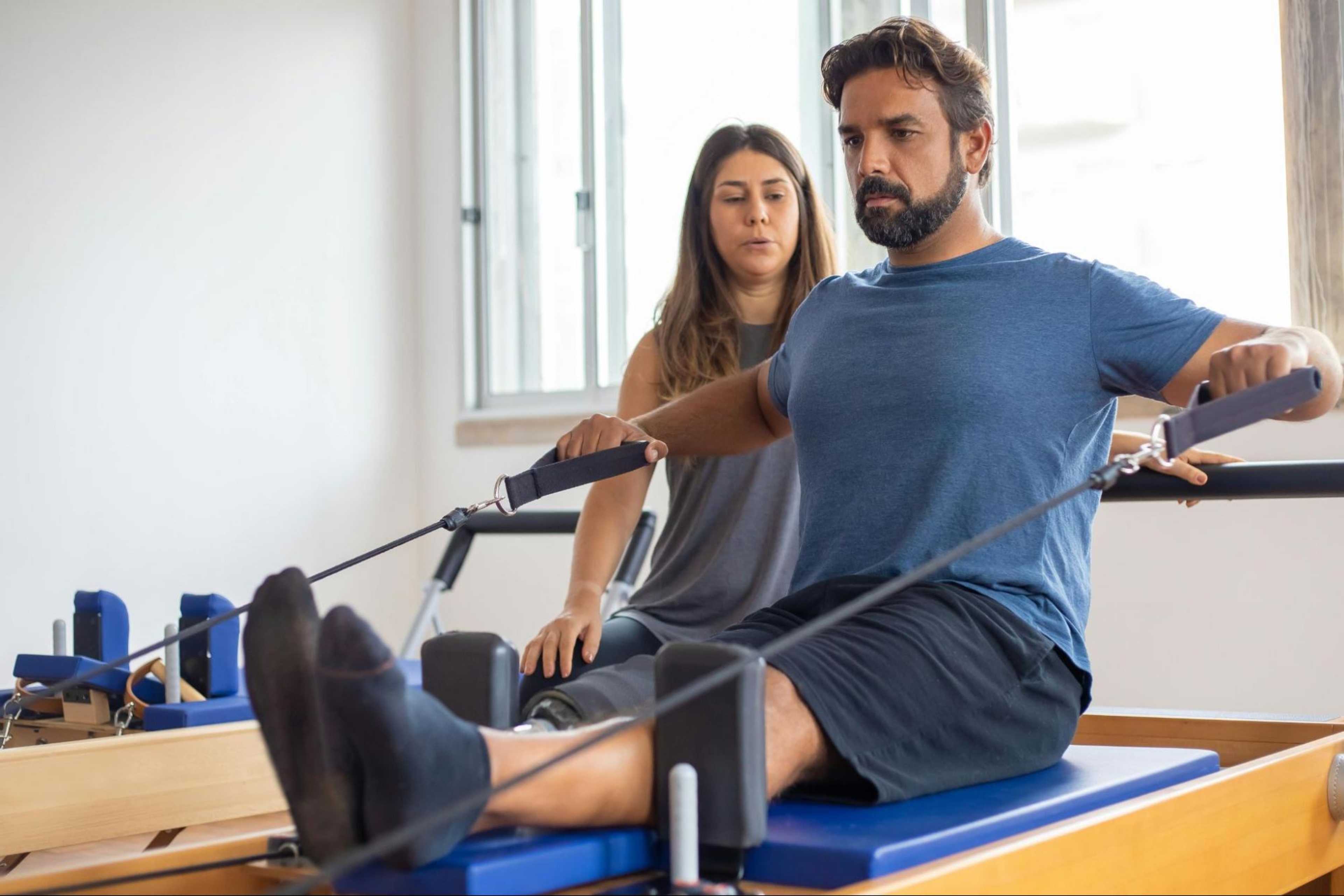 Man does a Pilates workout for strength training using a Reformer machine.