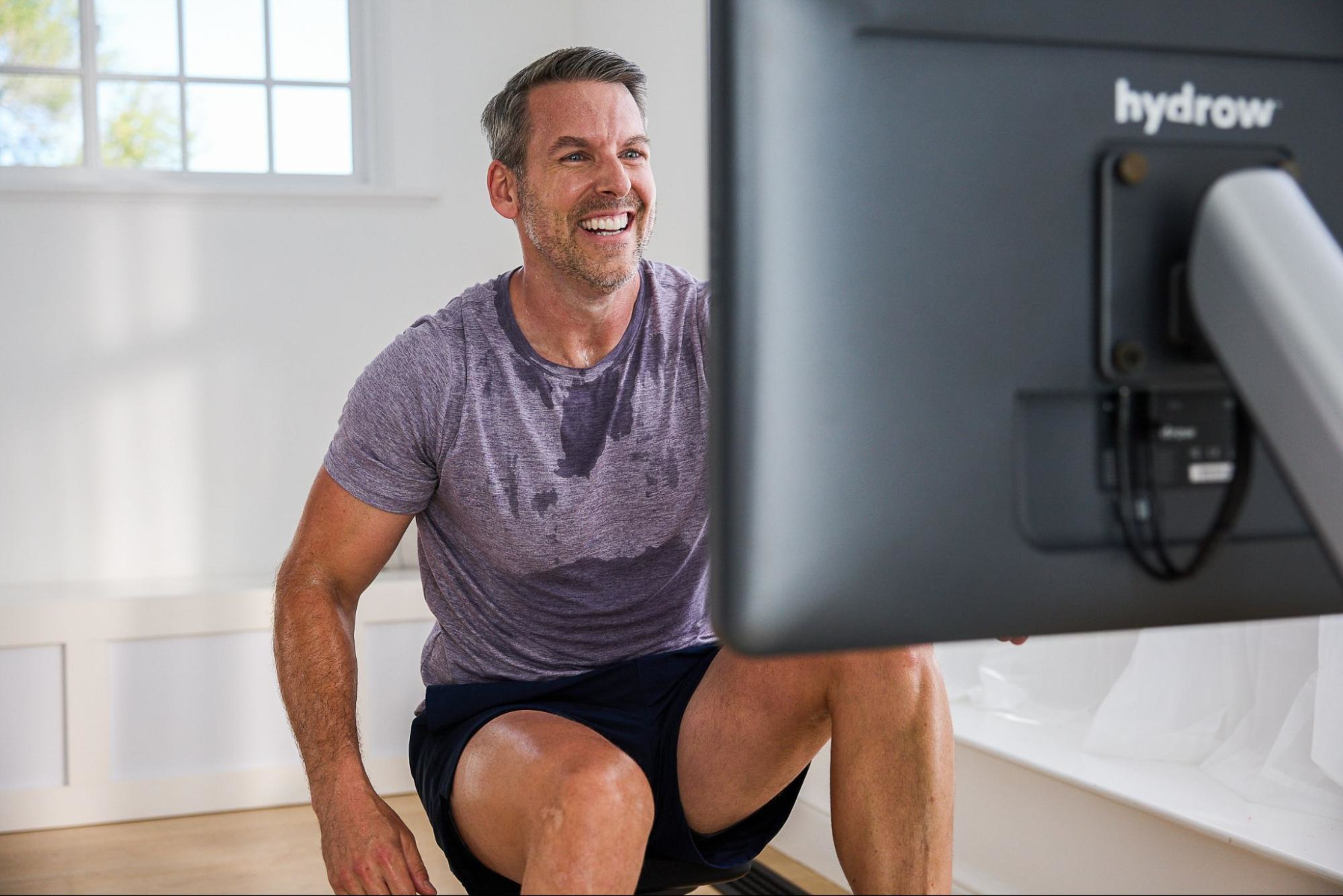 Man works out on a Hydrow rowing machine to reap the cardio benefits of rowing.