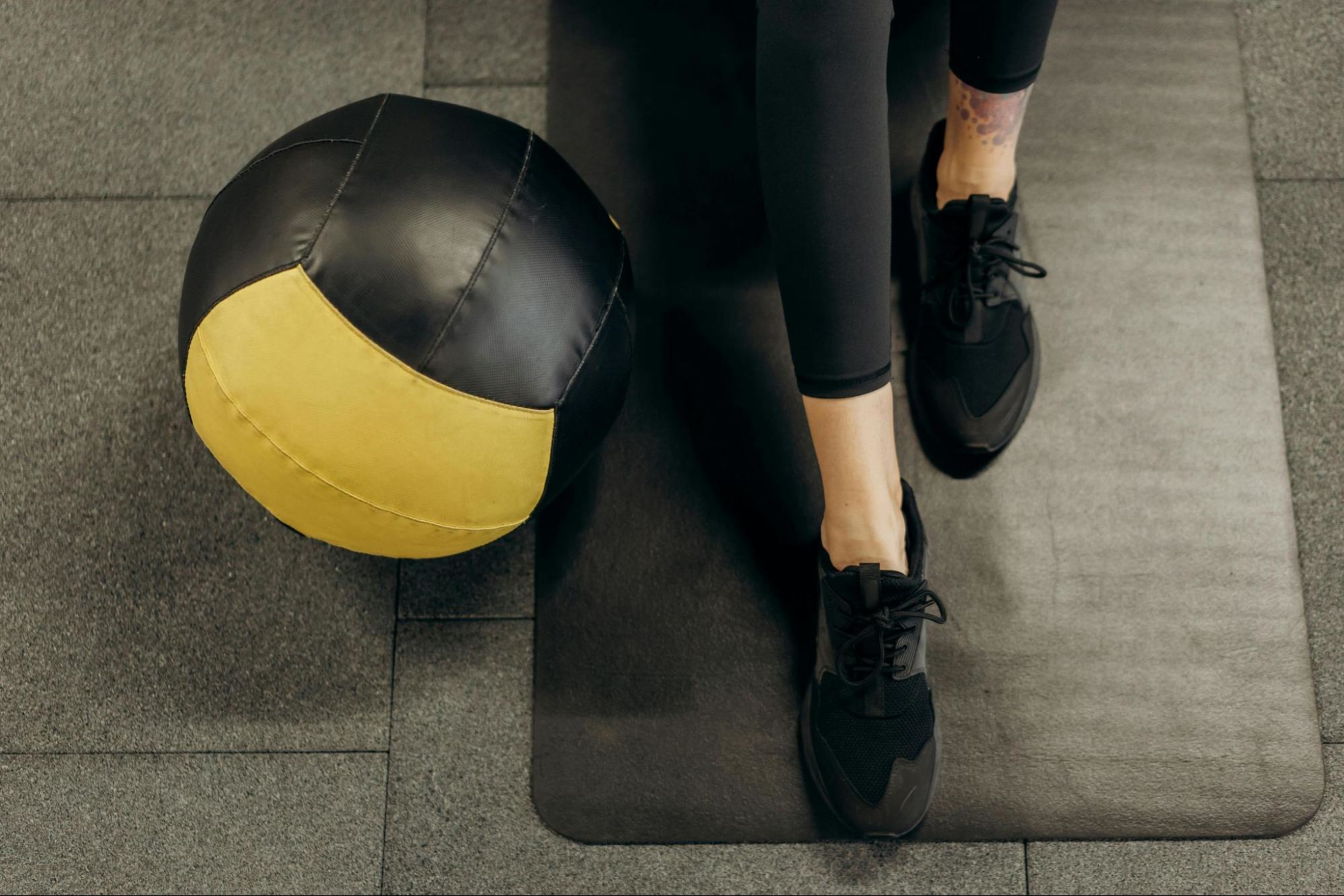 Woman works out with a medicine ball, a popular piece of at-home strength training equipment.