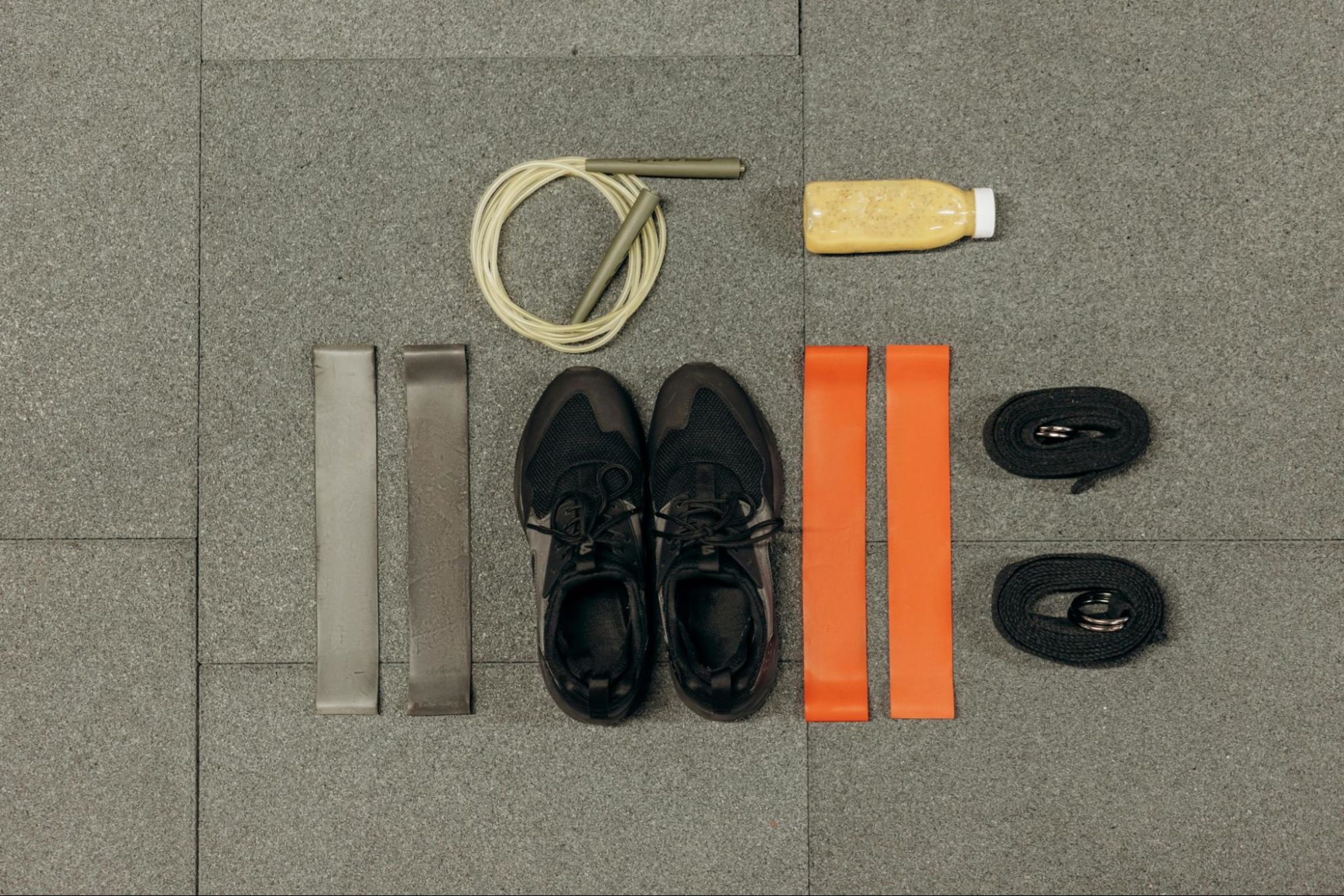 Resistance bands laid out on the ground next to sneakers and juice.