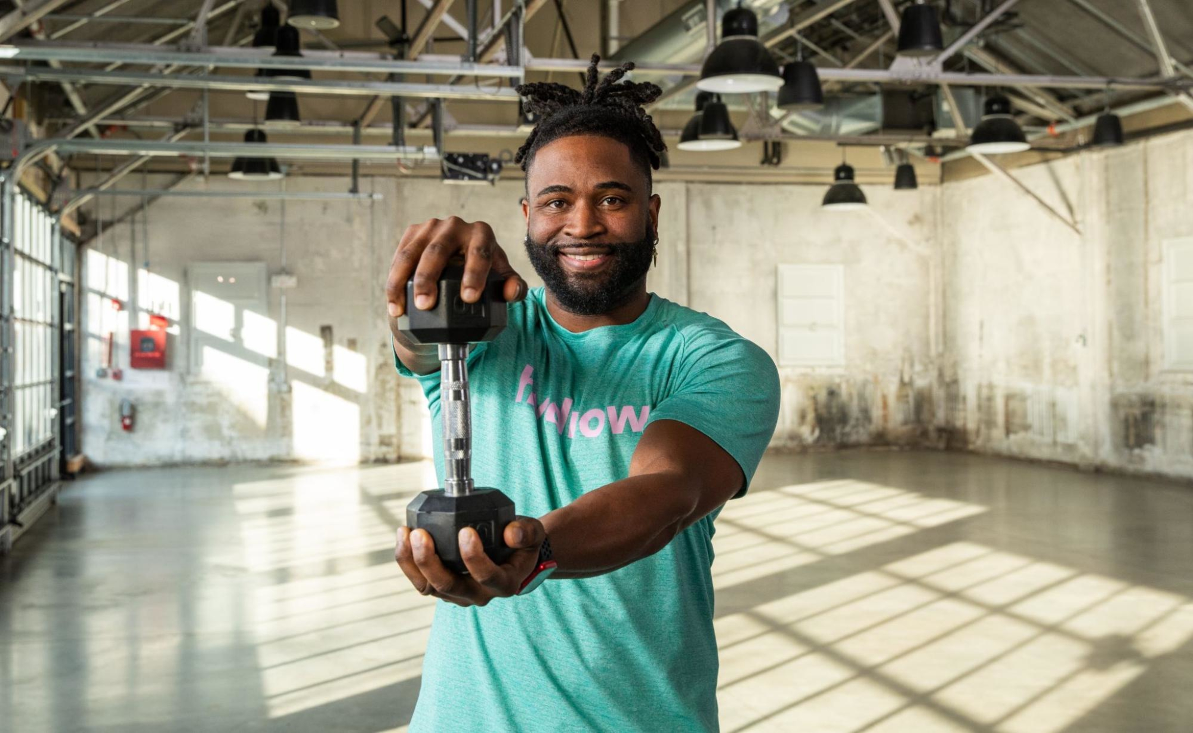 Hydrow Athlete Manteo demonstrates how to build strength by holding a dumbbell.