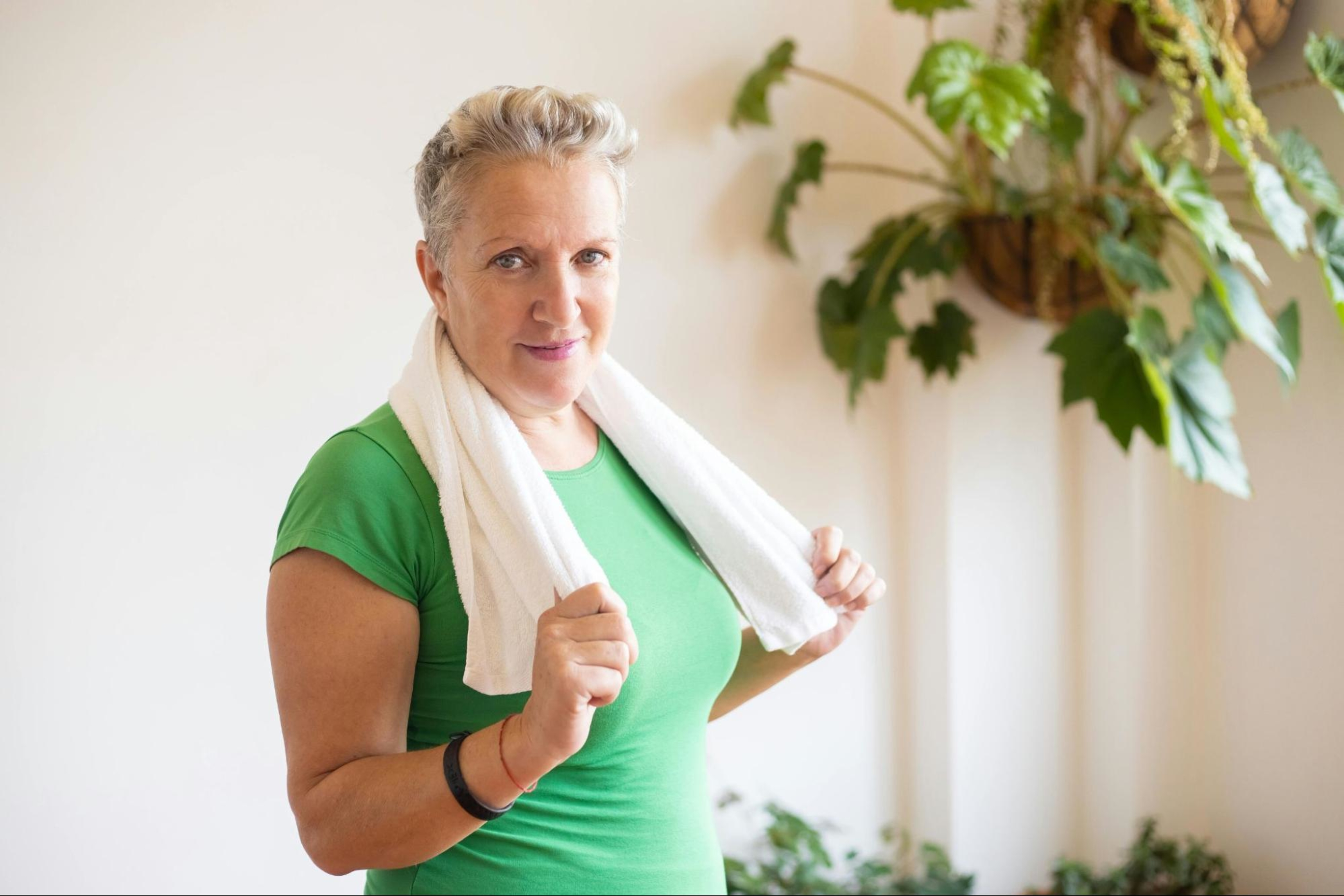 Woman over 50 wears a towel around her neck and prepares to do strength training exercises.