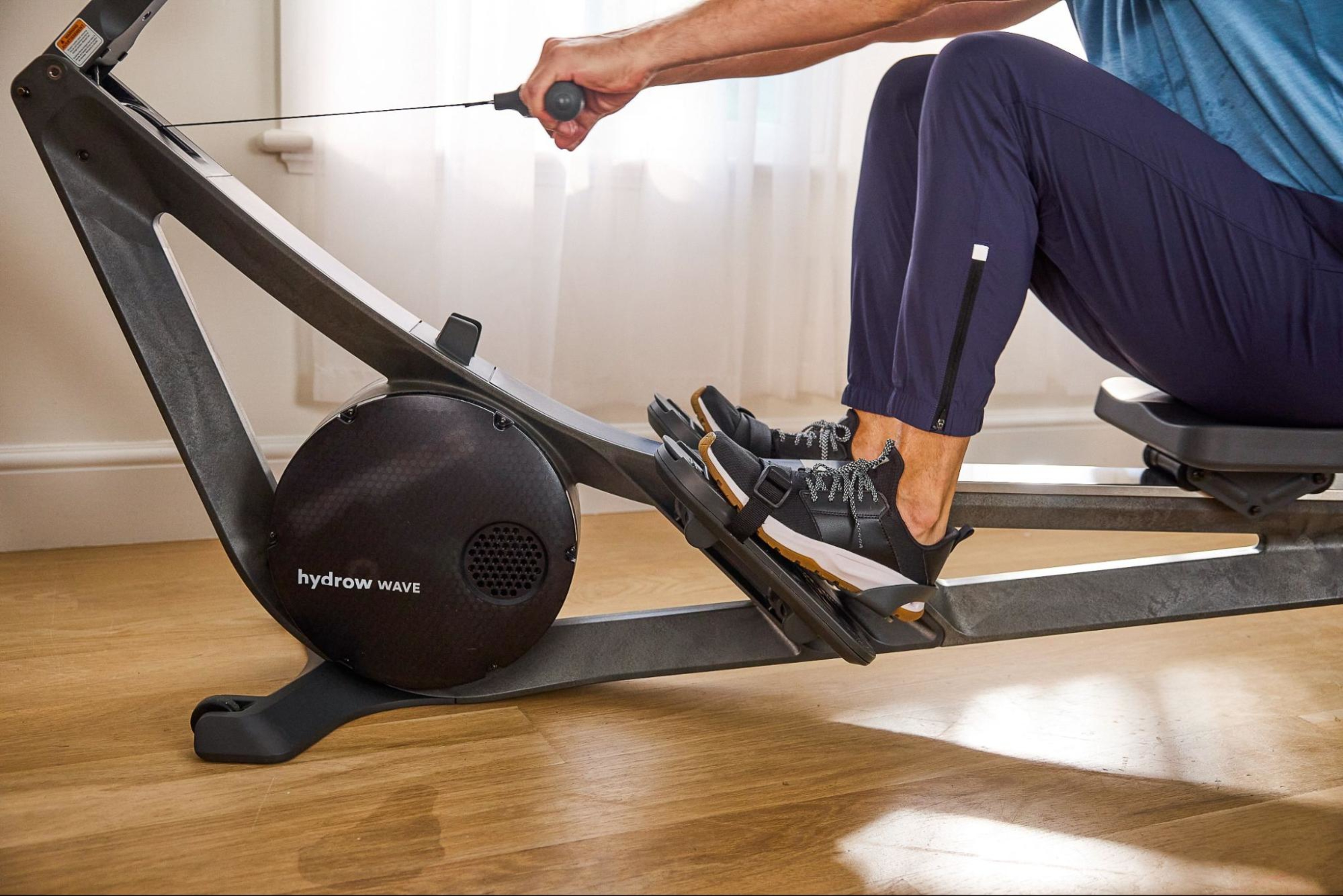 Man works out on a Hydrow rowing machine using the standard drag factor of 104.
