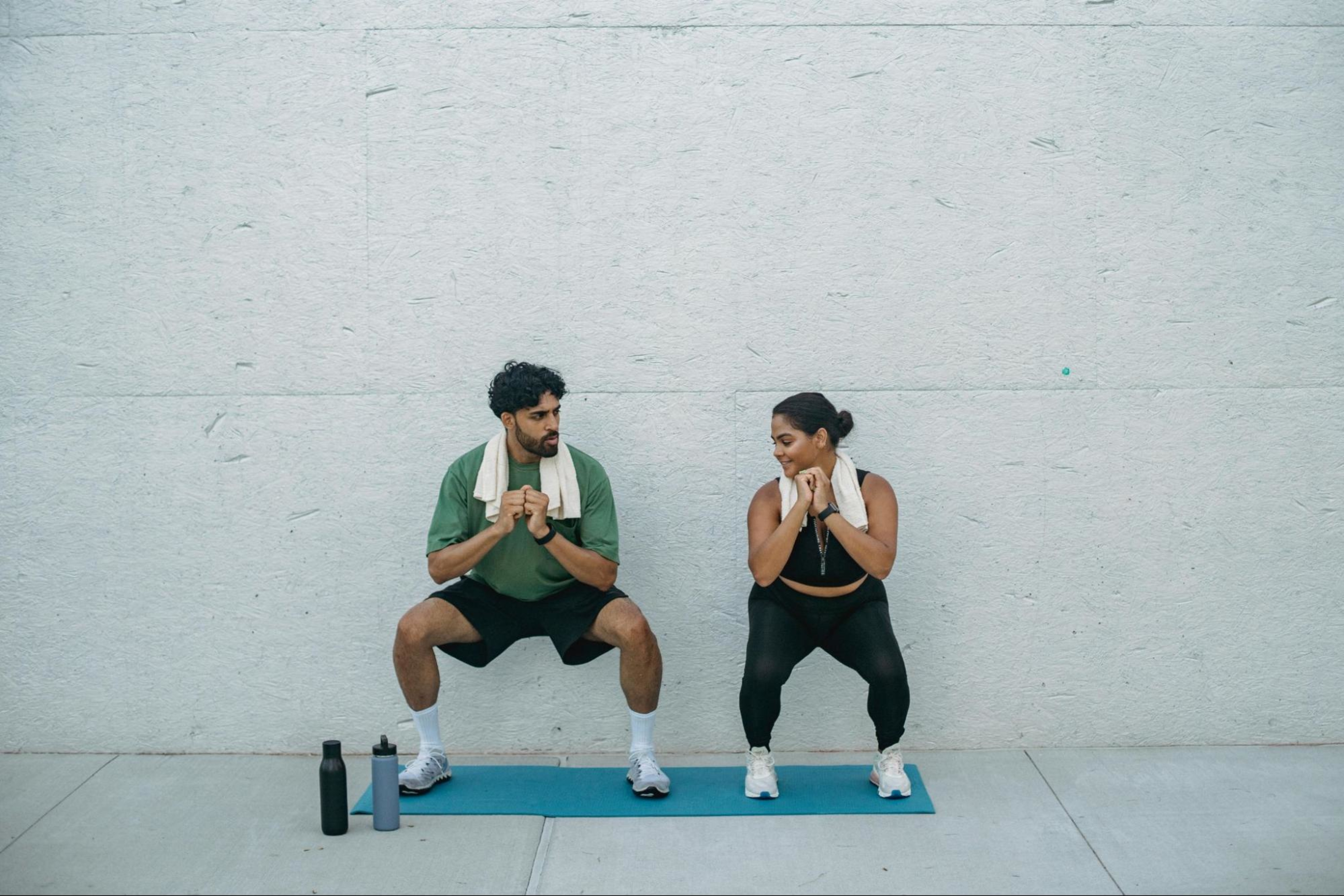 Man and woman do squats, an example of a low-impact strength training exercise.