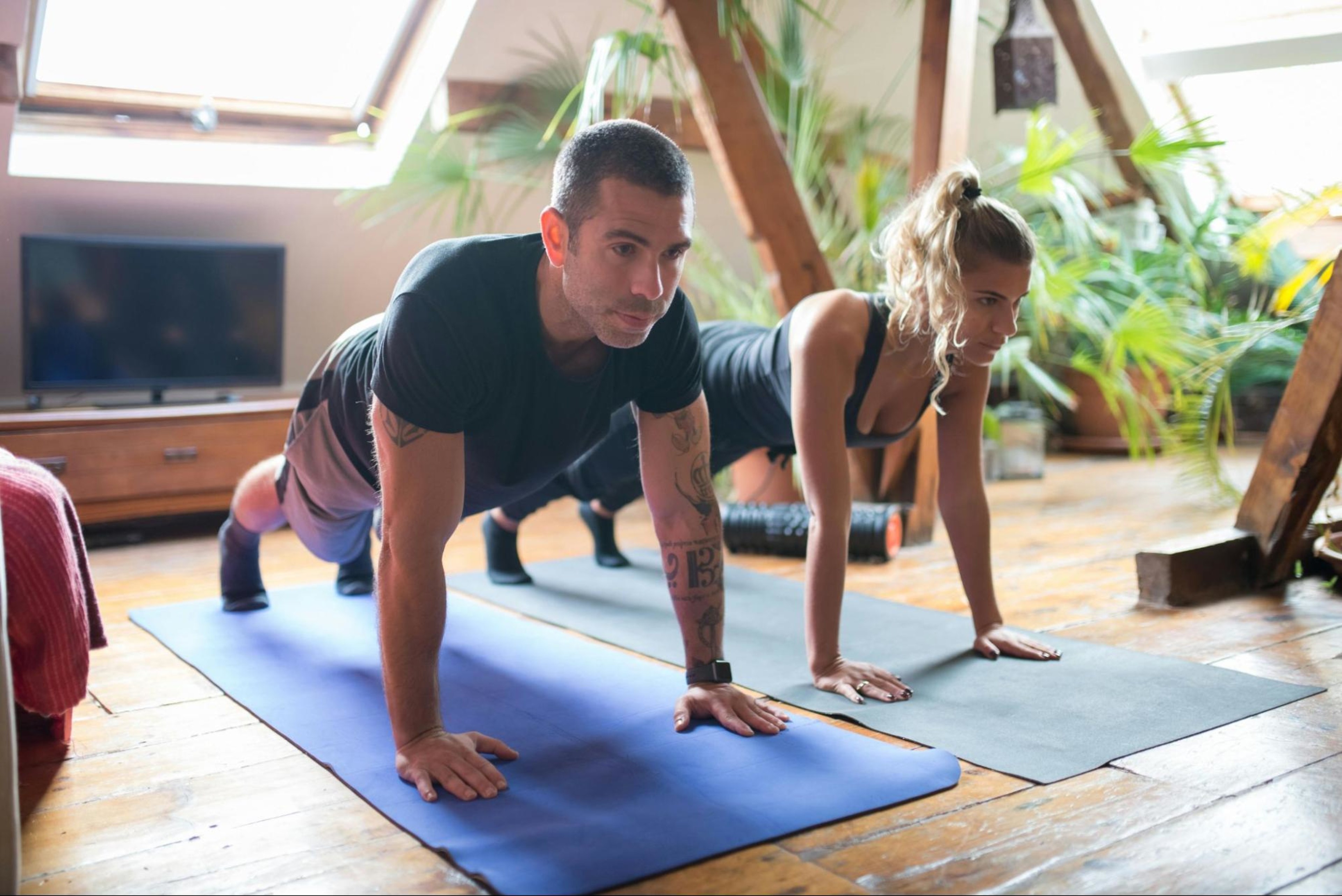 Couple does planks in their living room, a type of low-impact strength training.