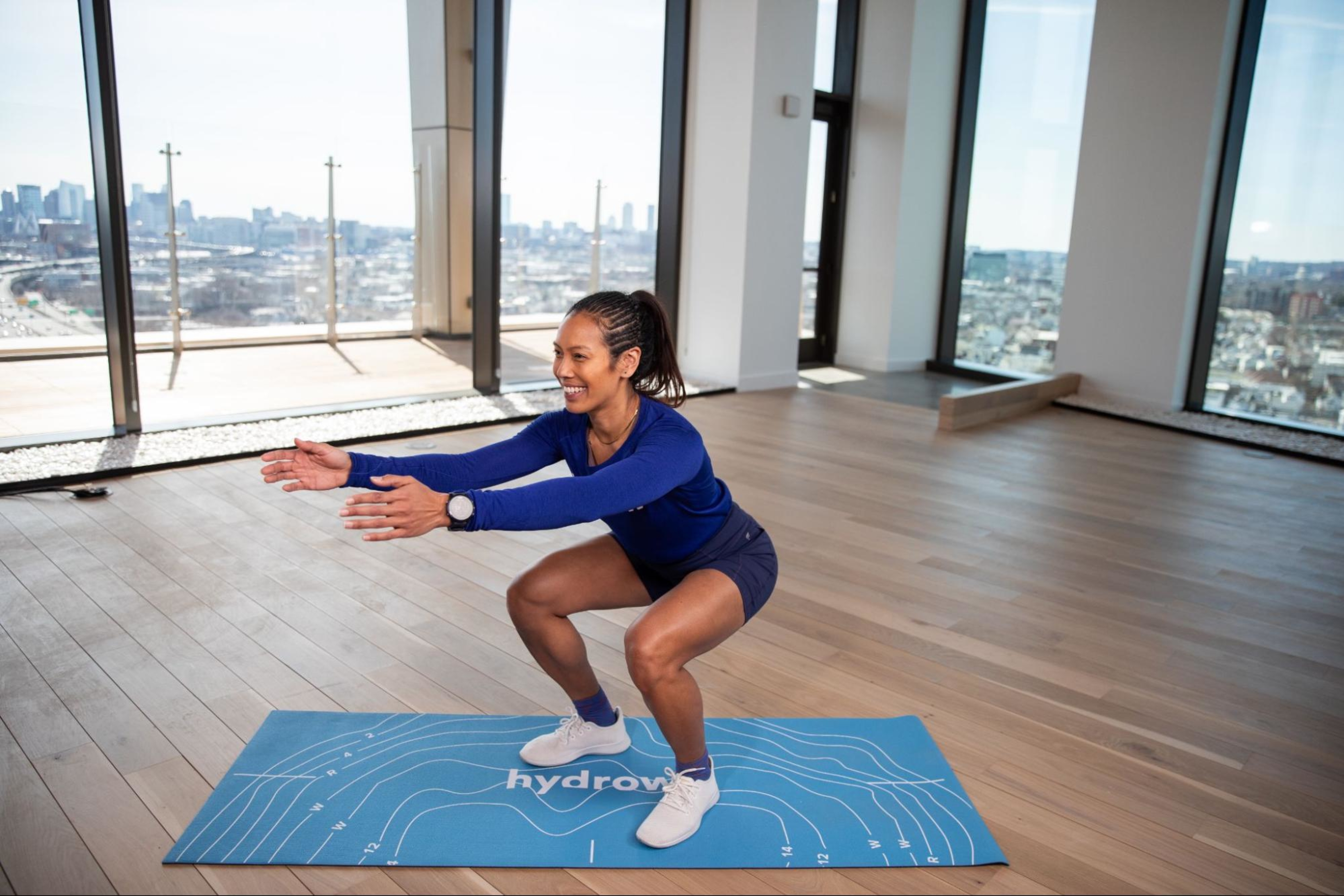 Hydrow Athlete demonstrates how to do a squat, a low-impact strength training exercise.