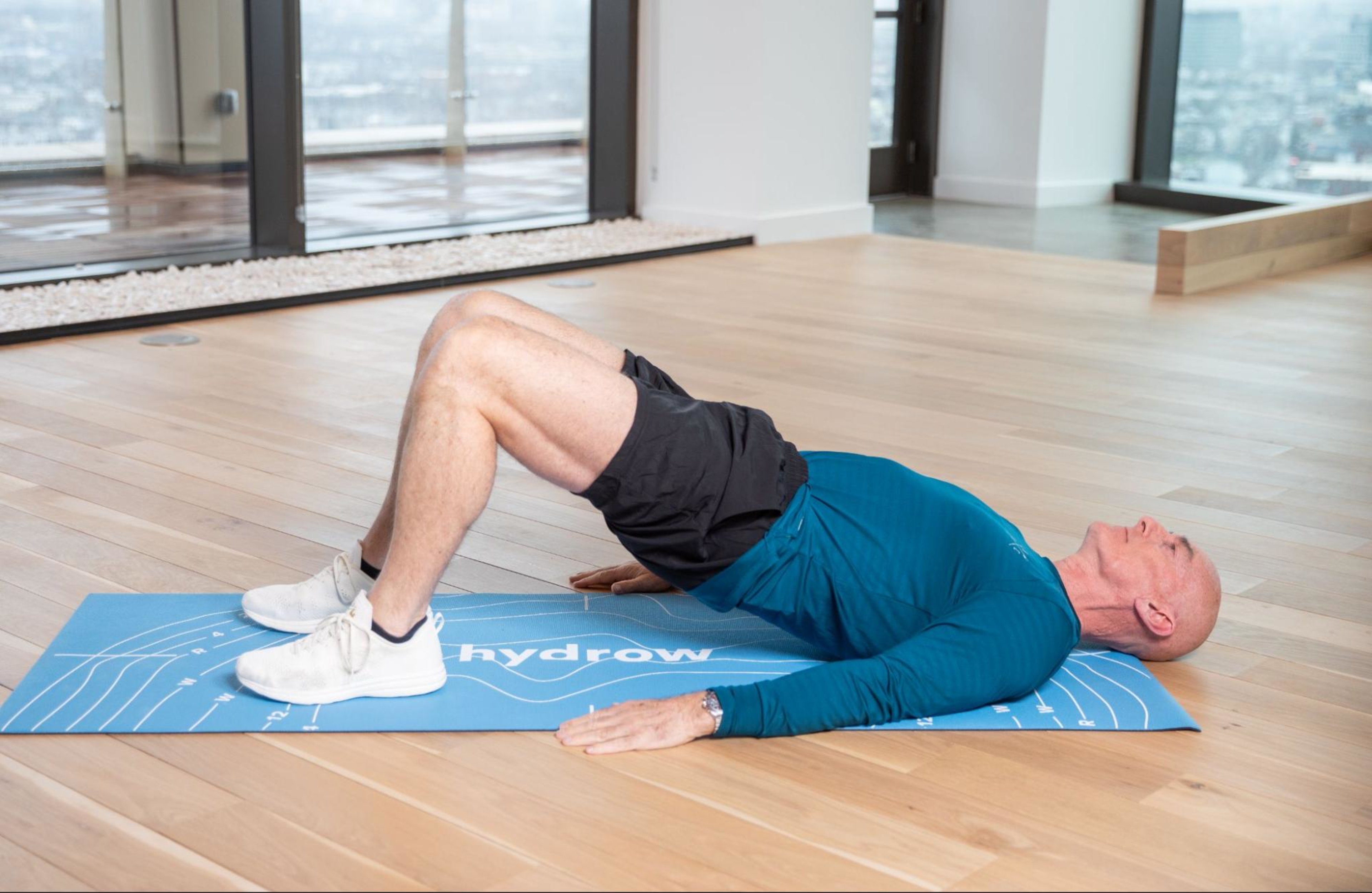 Hydrow Athlete demonstrates how to do a glute bridge, a type of low-impact strength training exercise.