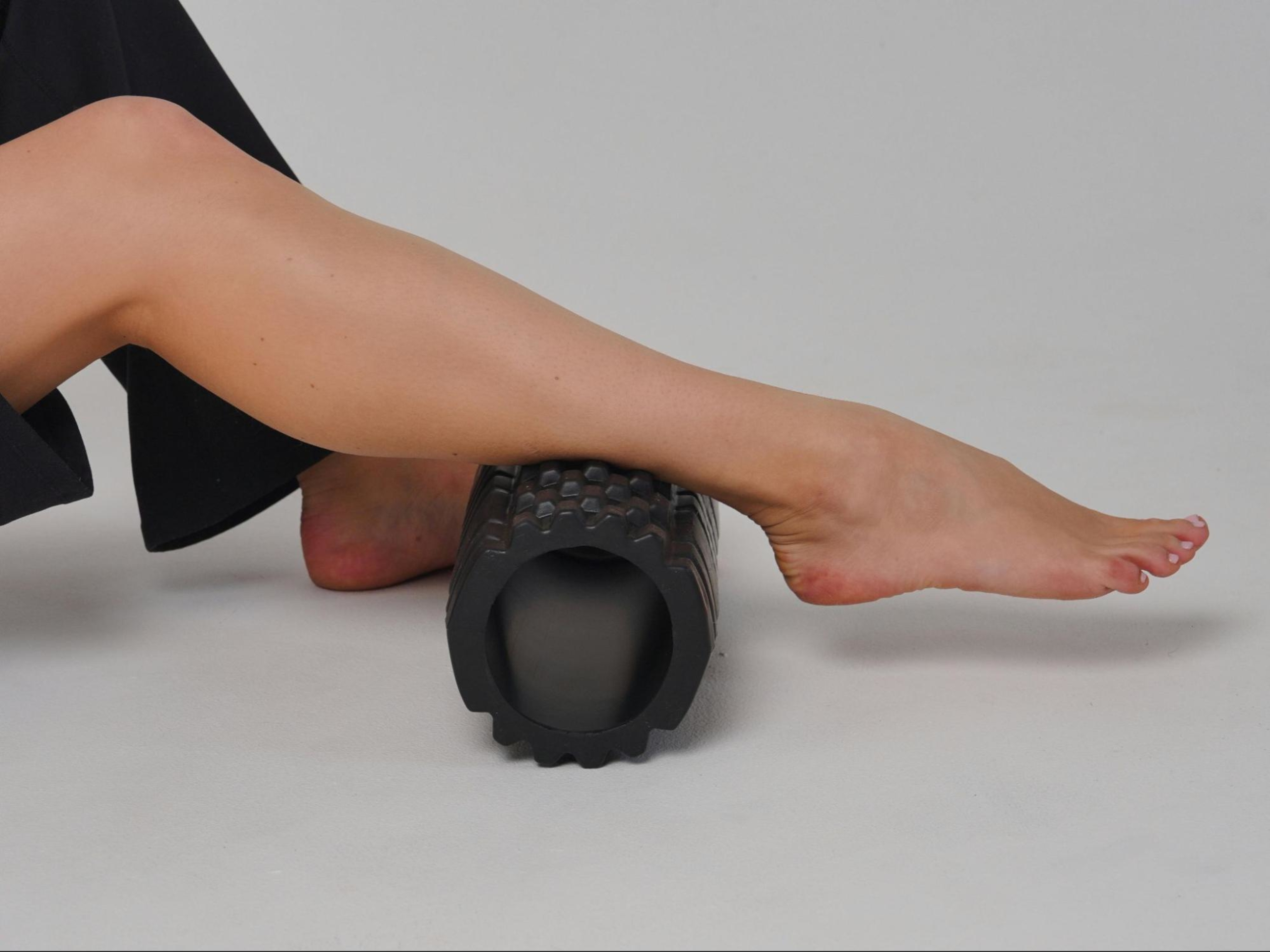 Woman demonstrates how foam rollers work on her calves.