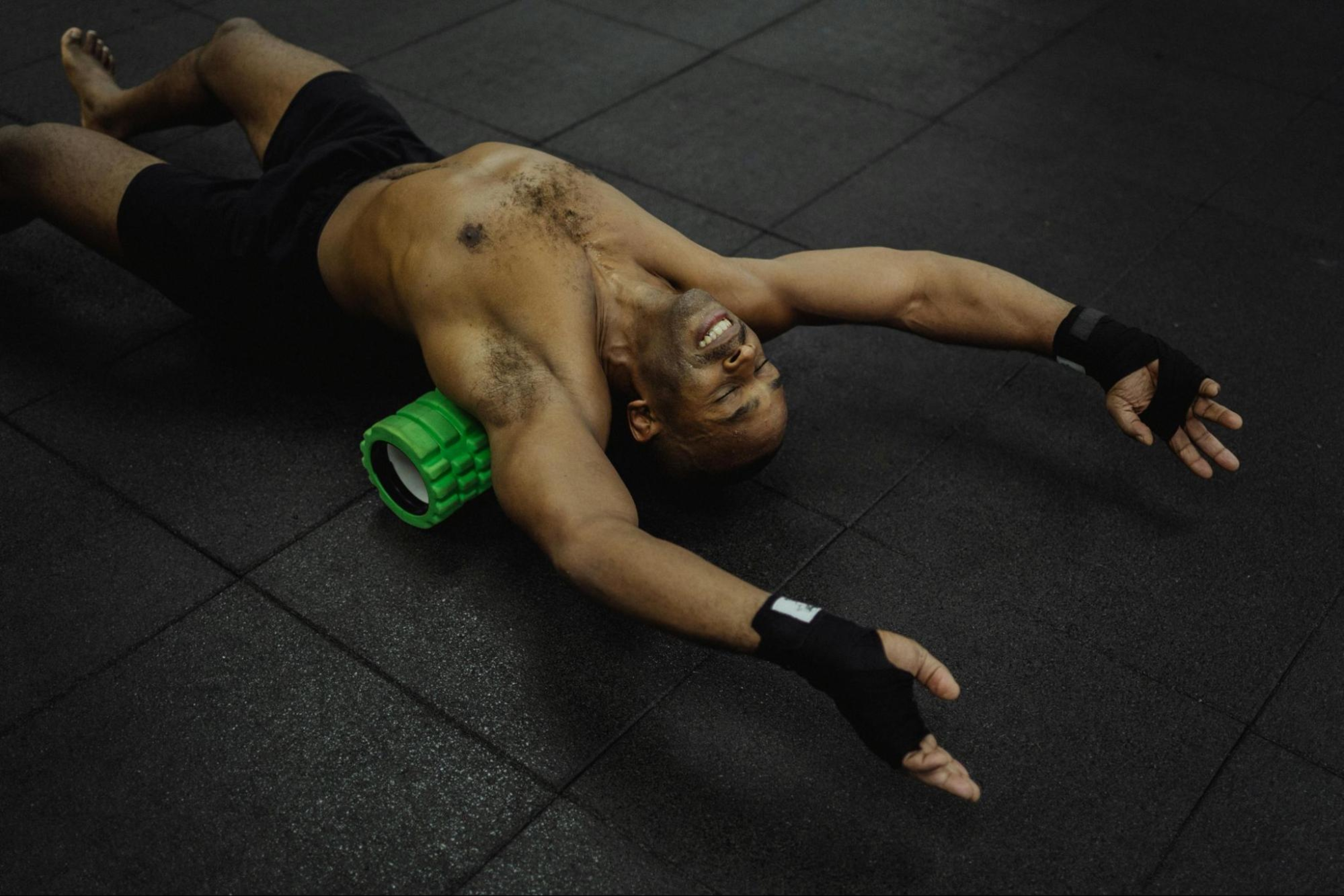 Man experiences the benefits of foam rolling on his back in a gym.