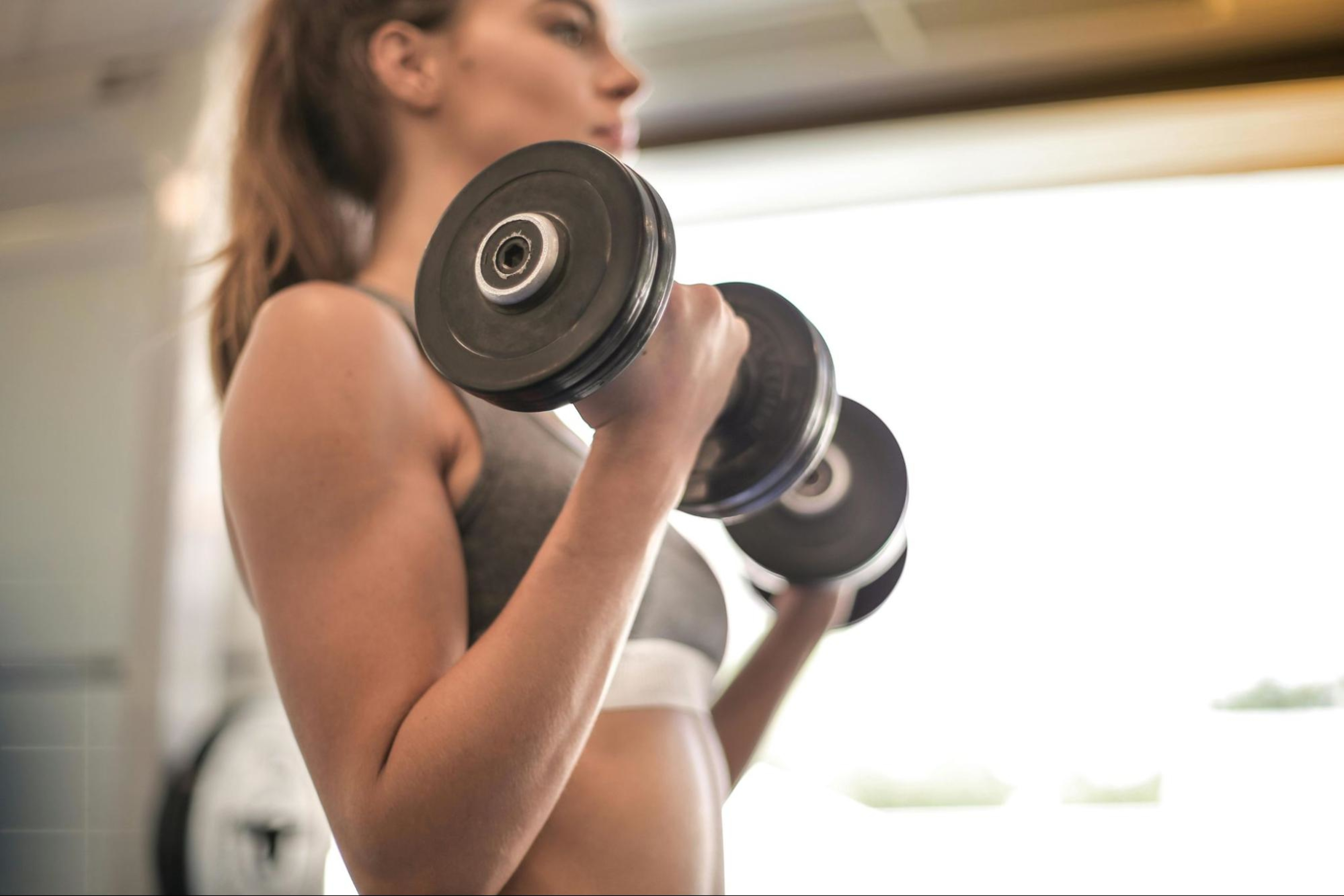 Woman does dumbbell exercises to build muscle in her forearms.