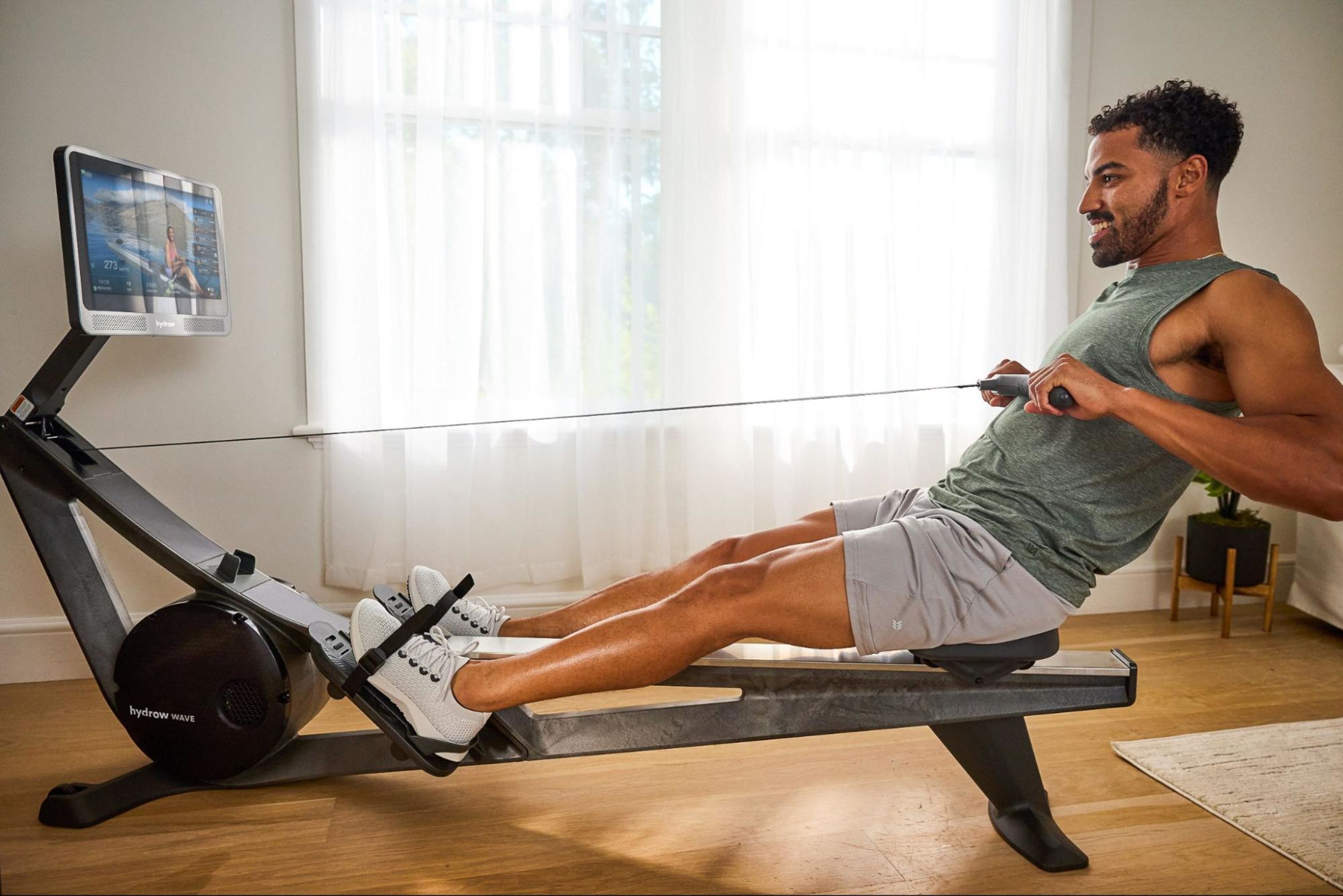 Man works out on a rowing machine to work his thighs, along with 86% of other muscles in his body.