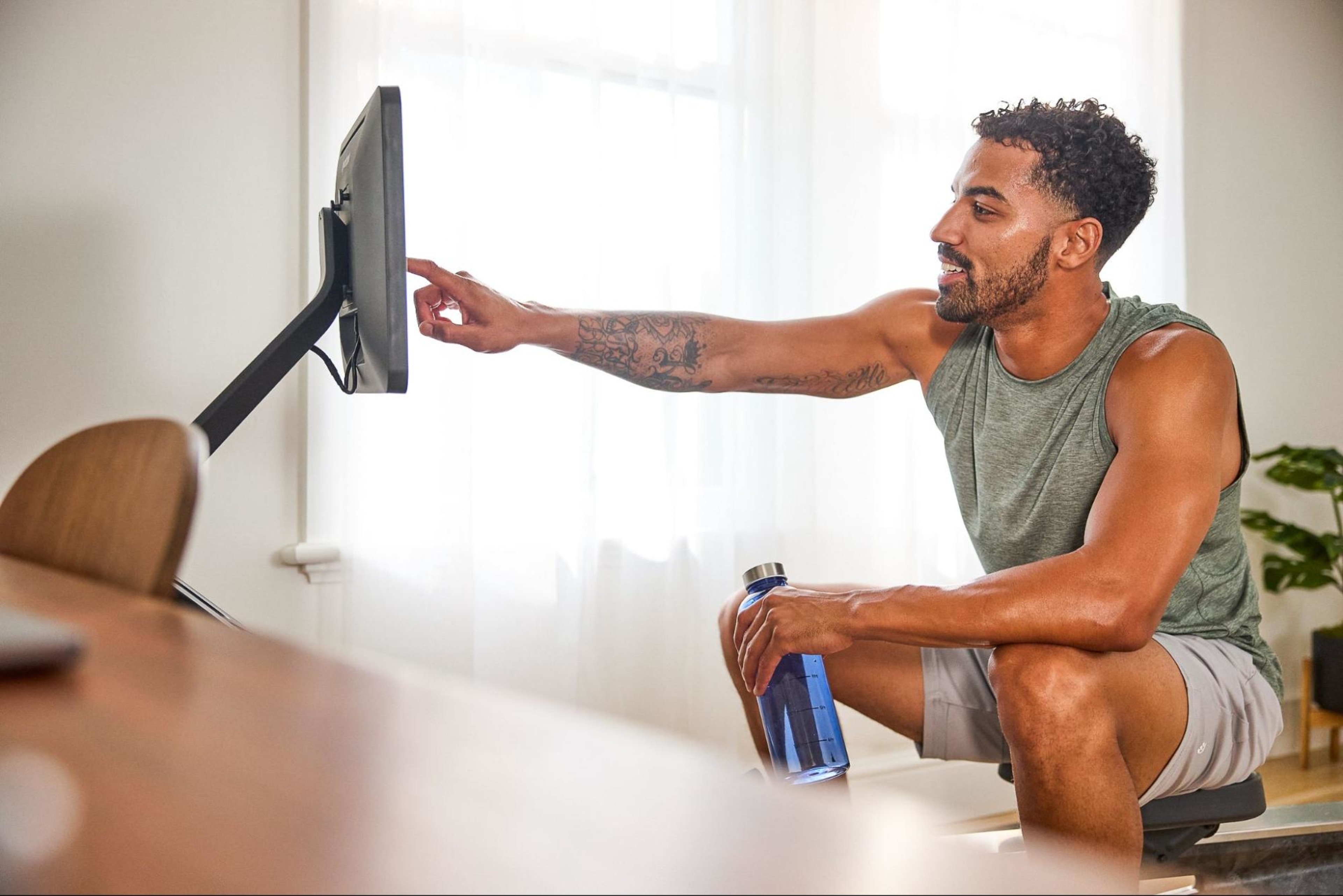 Man navigates to different workouts using his screen on his Hydrow Wave rowing machine.