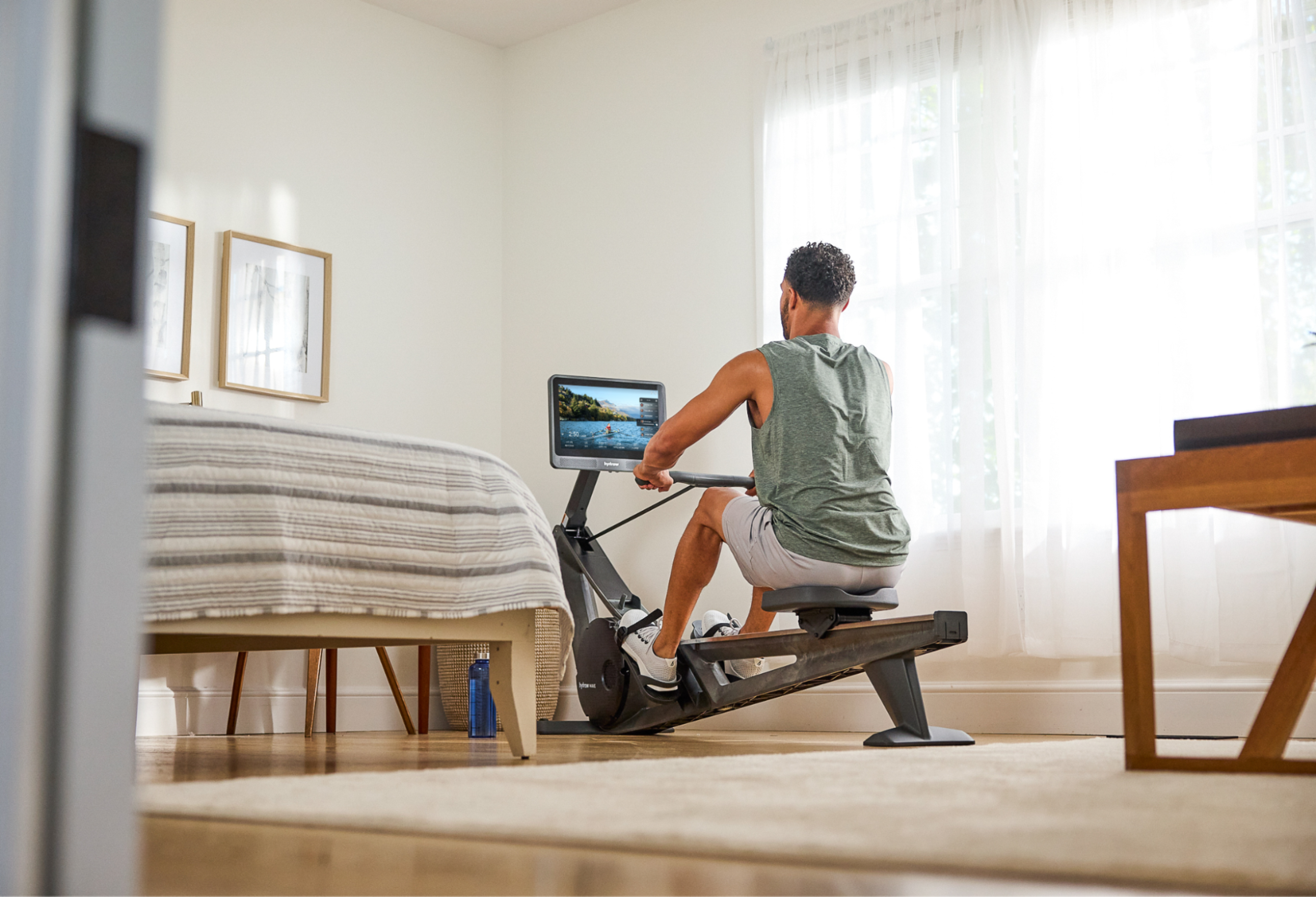 Man works out on a Hydrow Wave rowing machine, which has smooth, quiet operation.