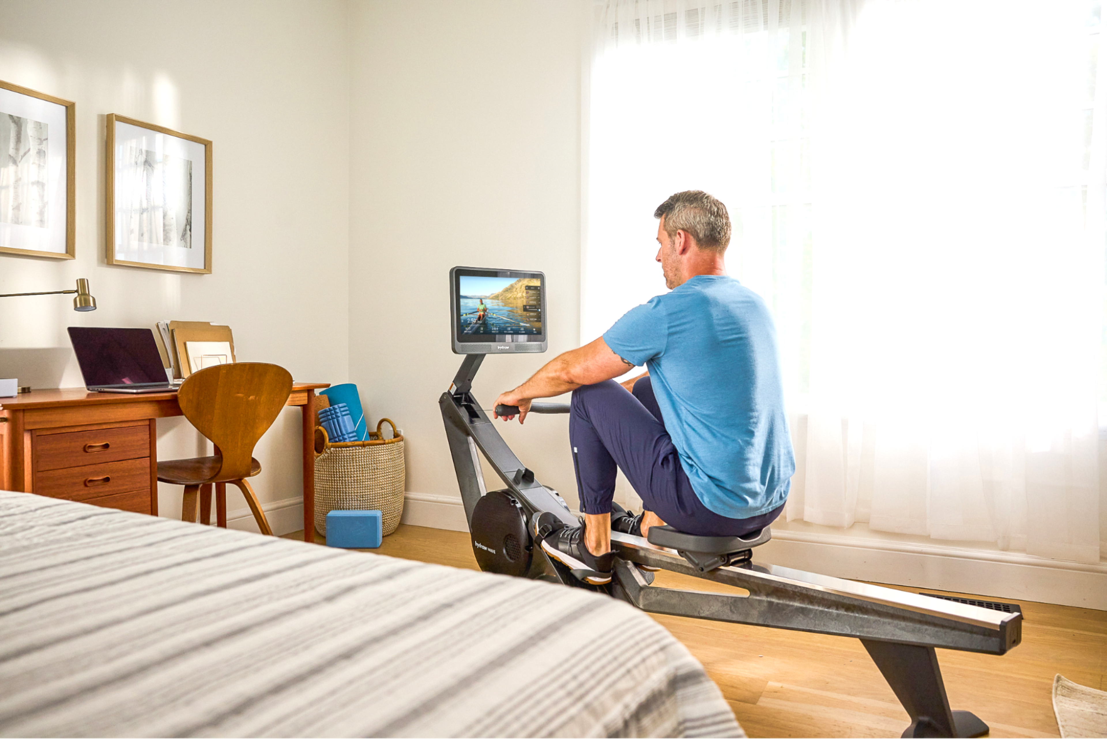Man works out on a Hydrow rowing machine, using the immersive display to follow along with a rowing workout.
