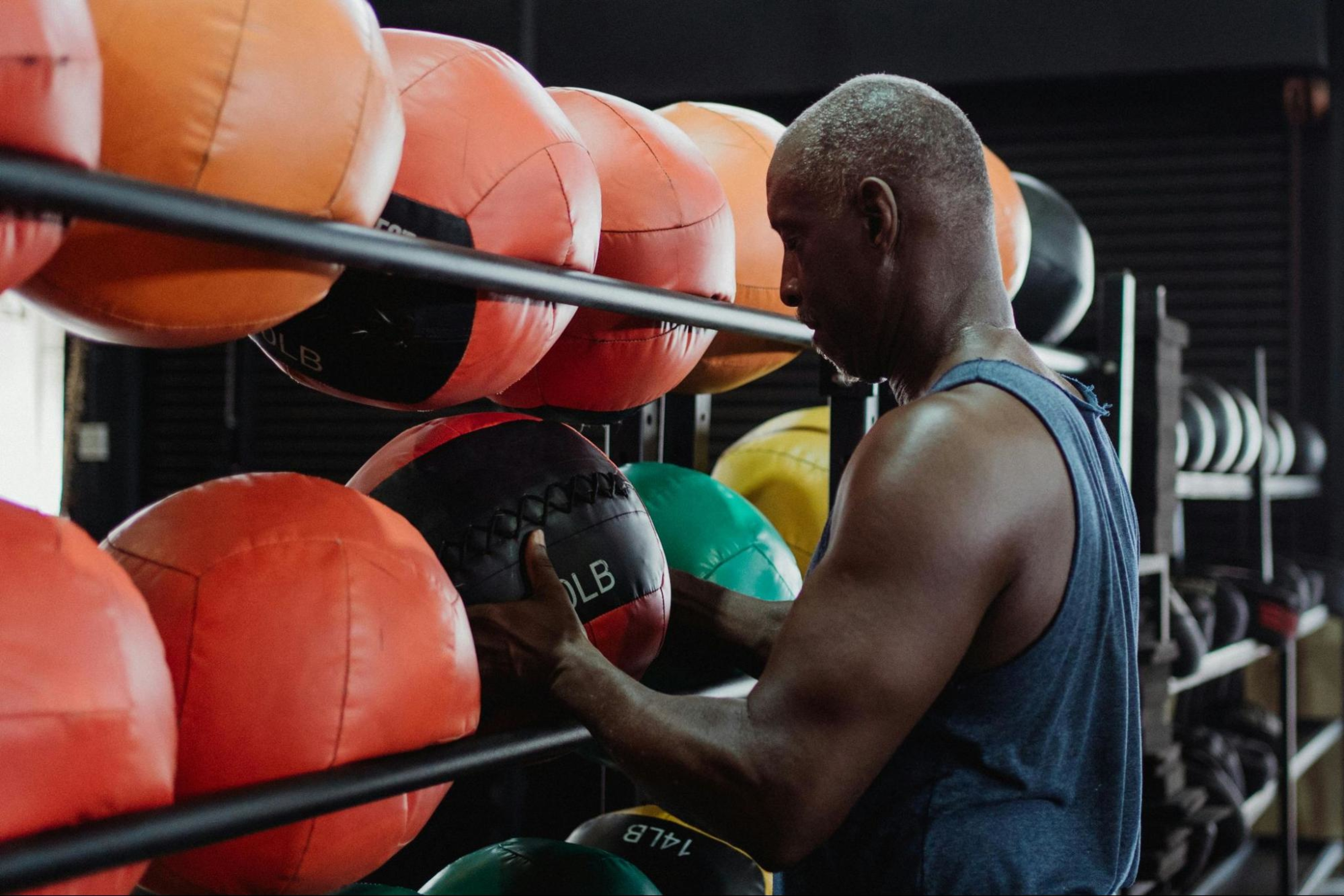 Man learns how to build muscle in arms by getting ready to do a medicine ball workout in a gym.