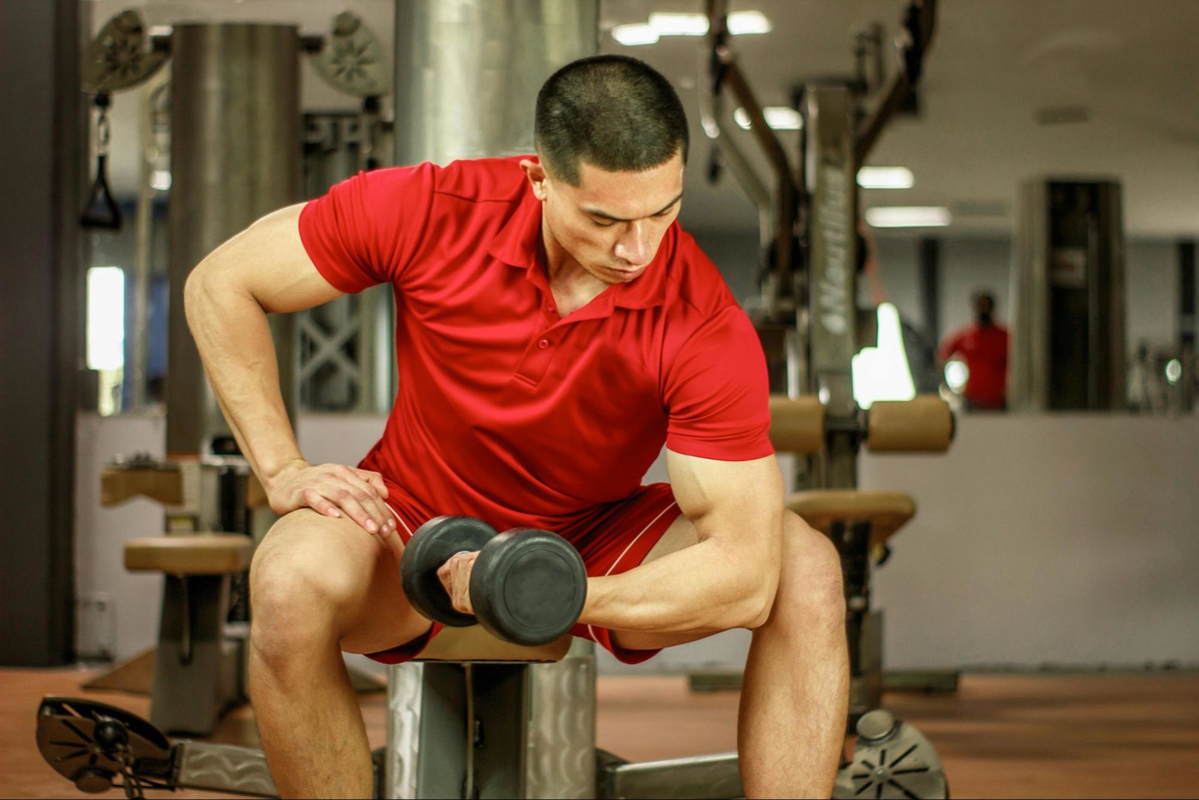 Man learns tips for increasing arm muscle by working out with a dumbbell in a gym.