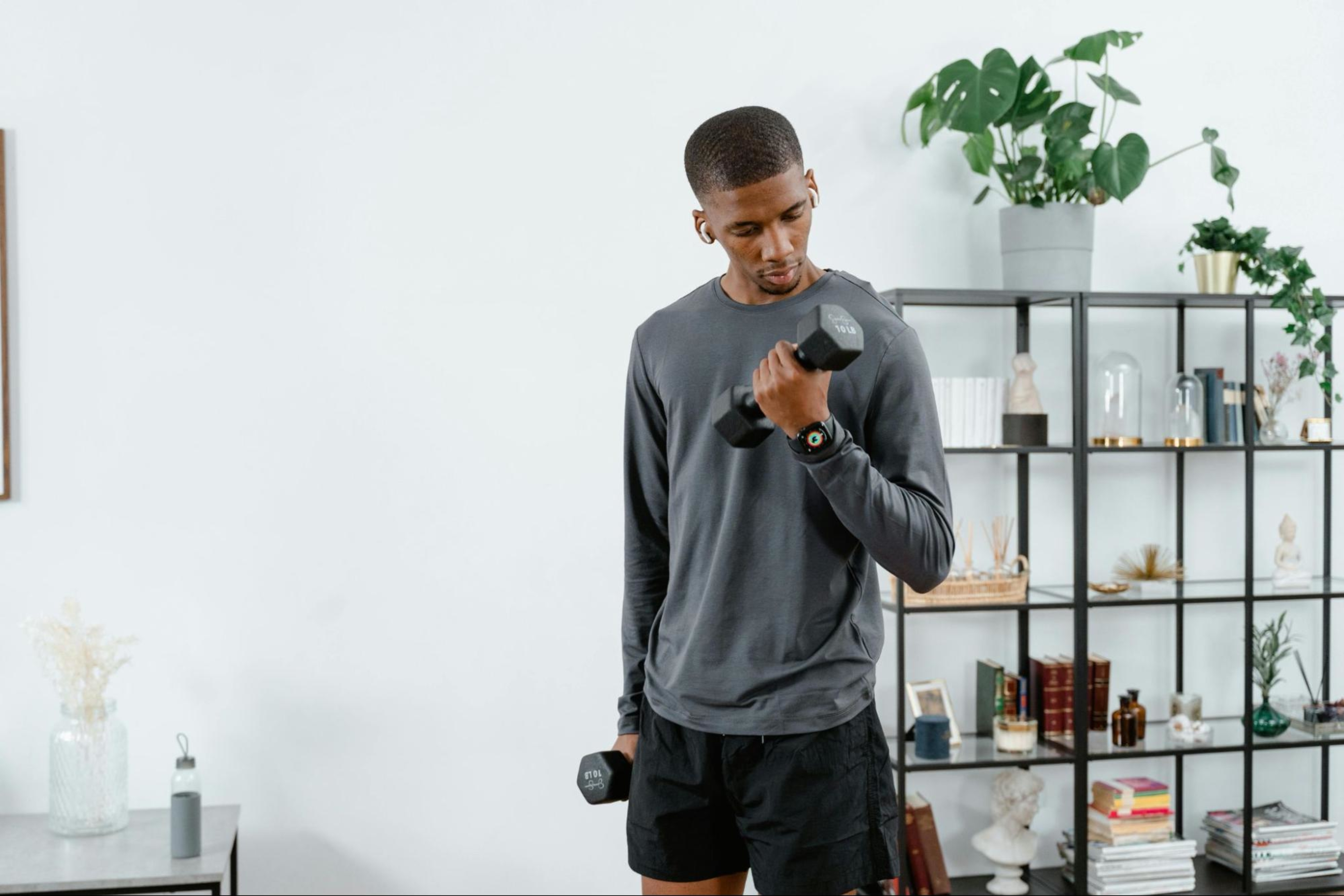 Man learns how to breathe while weight training while working out with dumbbells in his living room.