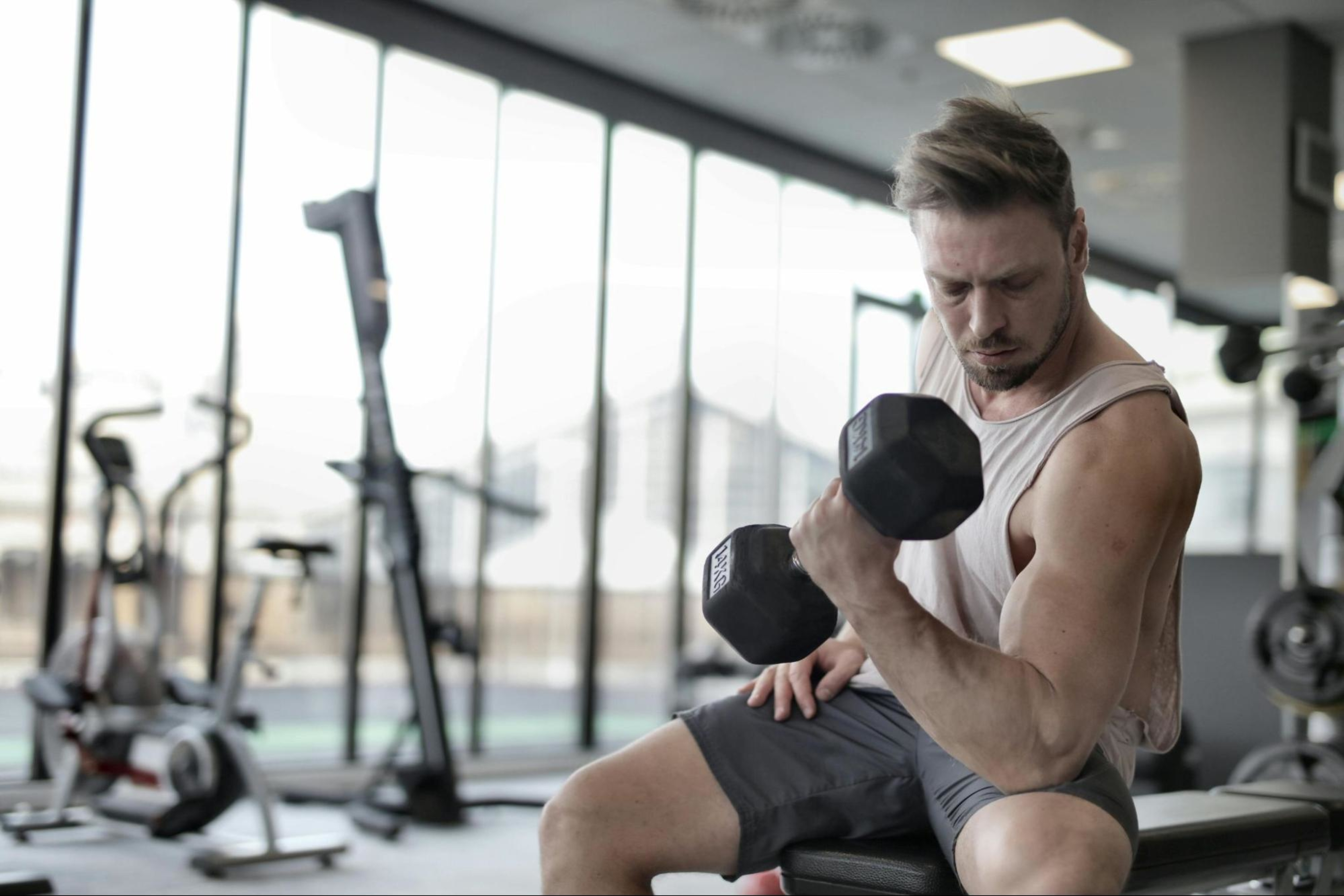 Man uses bicep workout ideas to craft a dumbbell workout routine in a gym.