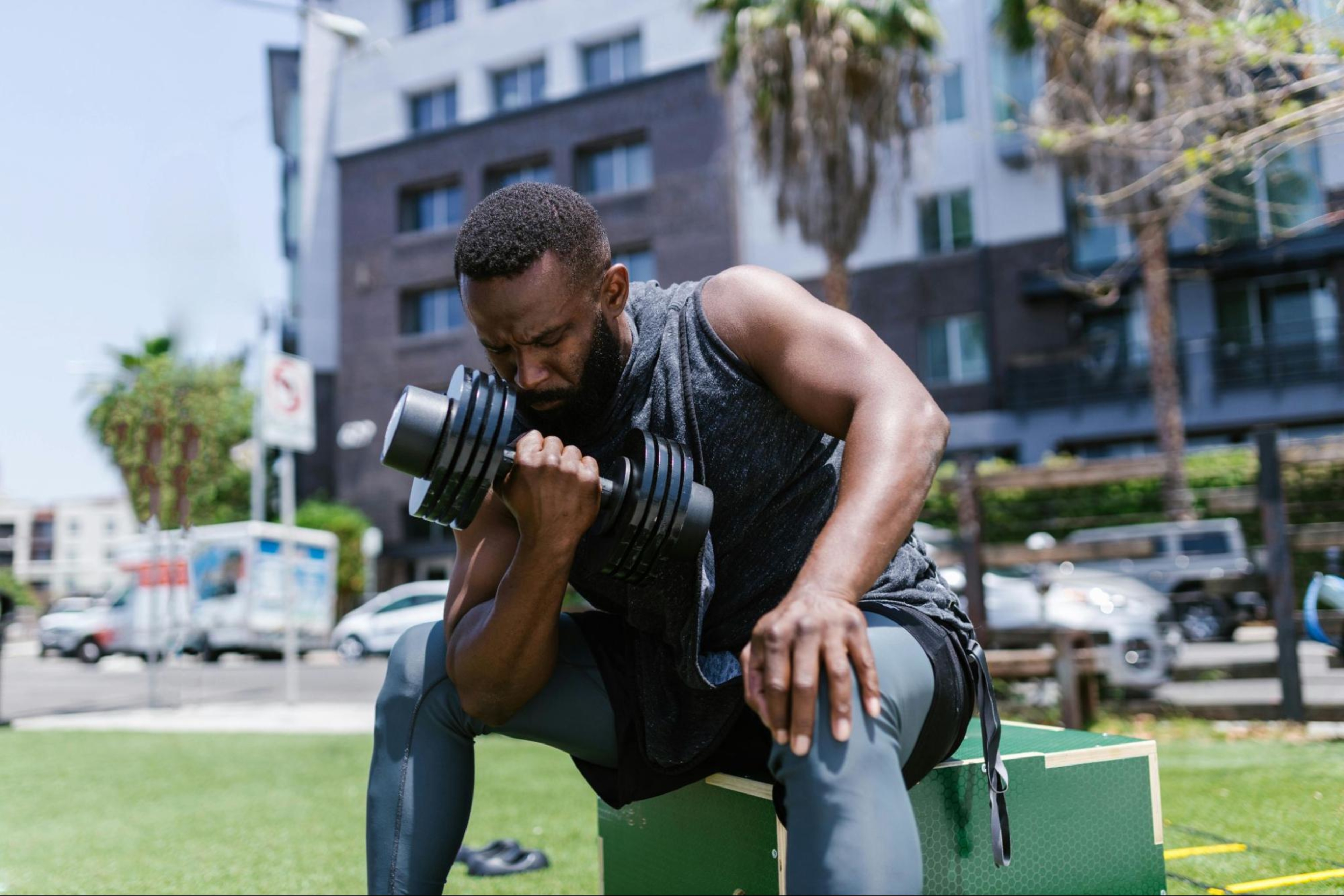 Man does a bicep workout outdoors with a dumbbell.