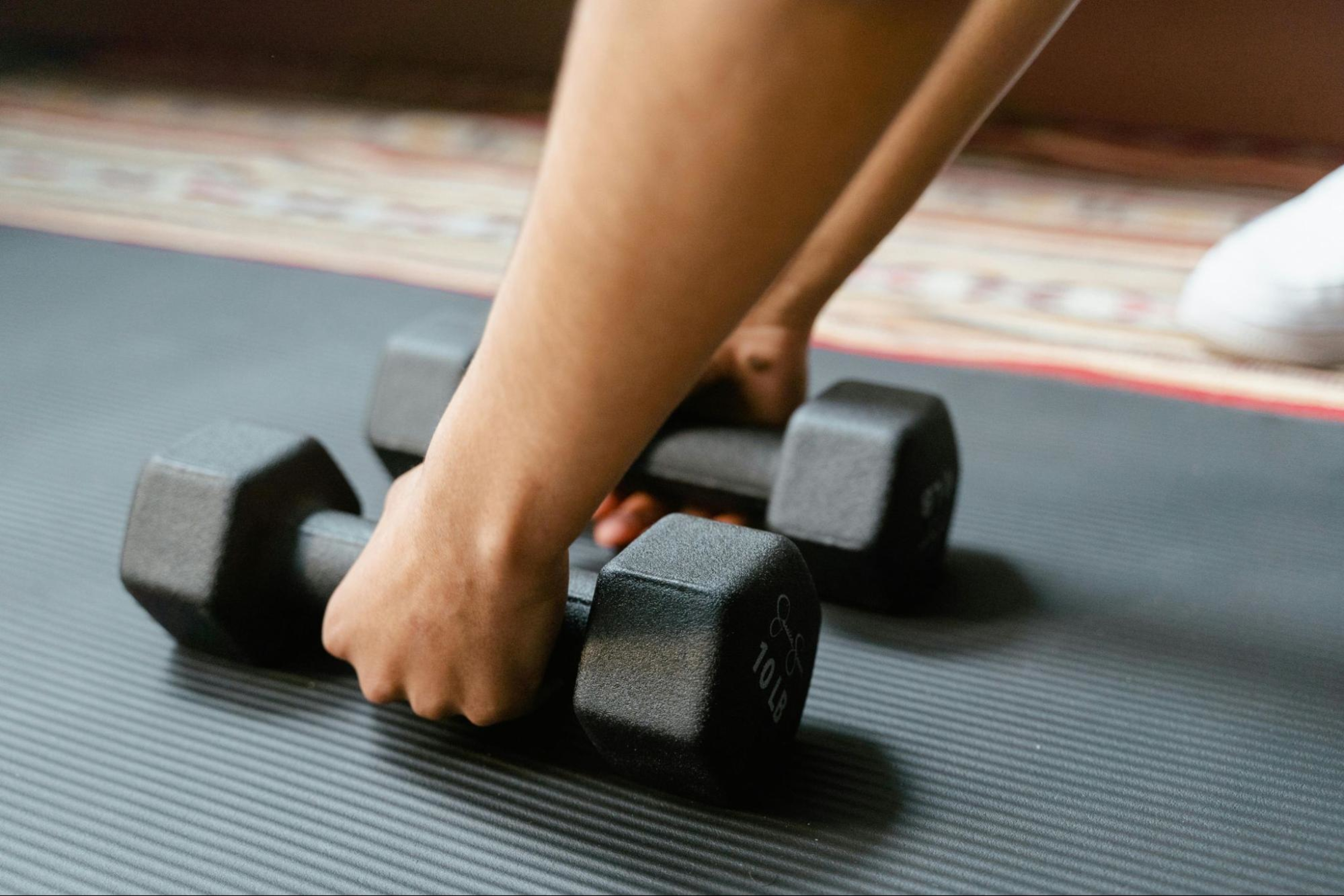 Woman grabs two dumbbells as she prepares to do good workouts for biceps.