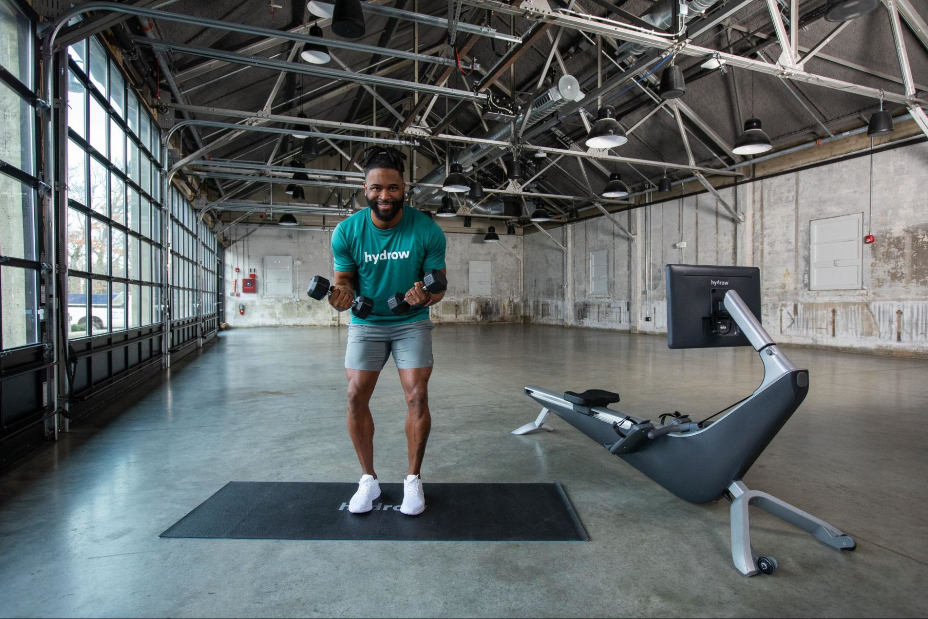 Hydrow Athlete demonstrates how to do bicep workouts with two dumbbells in a gym.