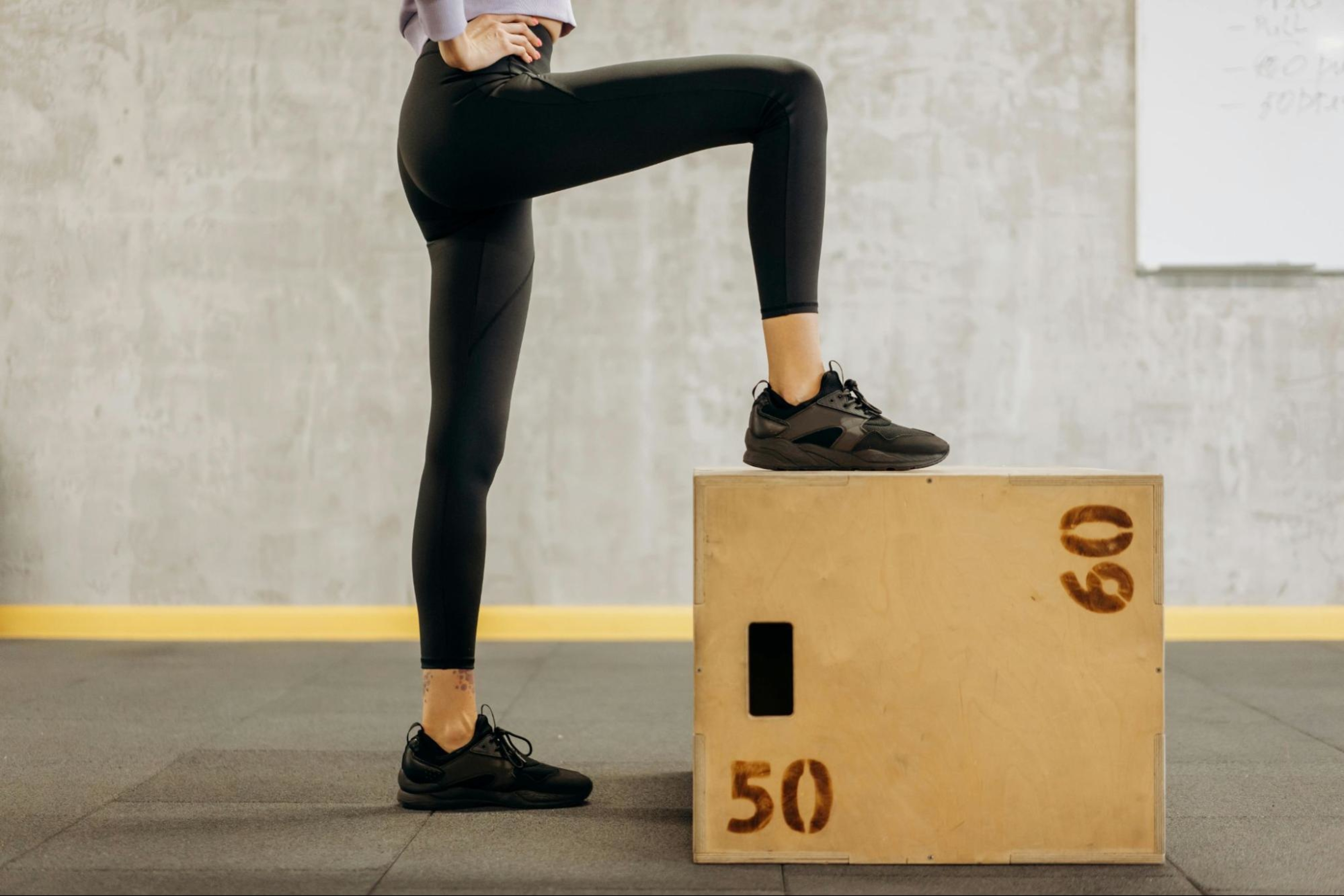 Woman follows tips for building leg muscle as she does box jumps.