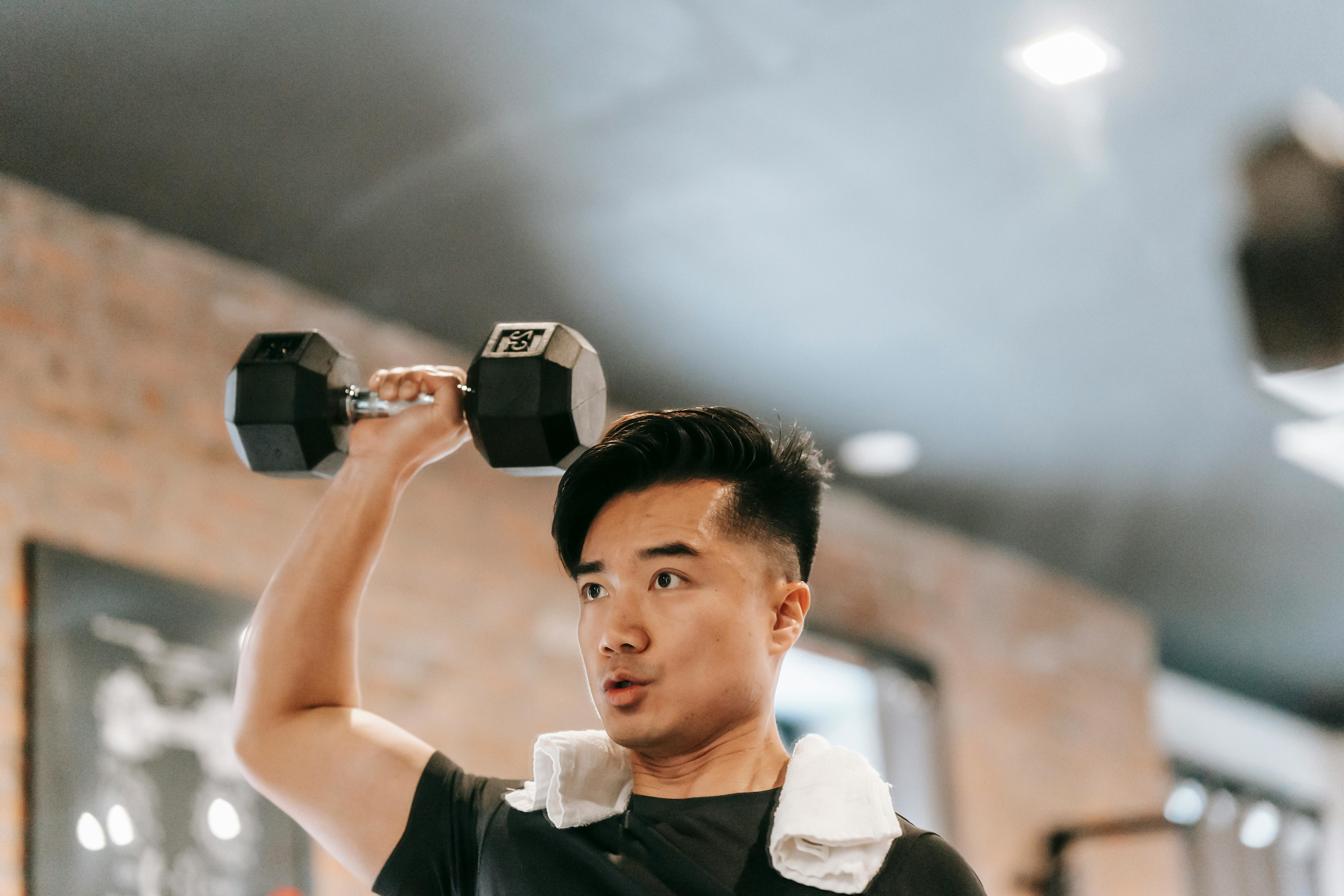Man works to avoid common biceps workout mistakes as he lifts a dumbbell with one hand.