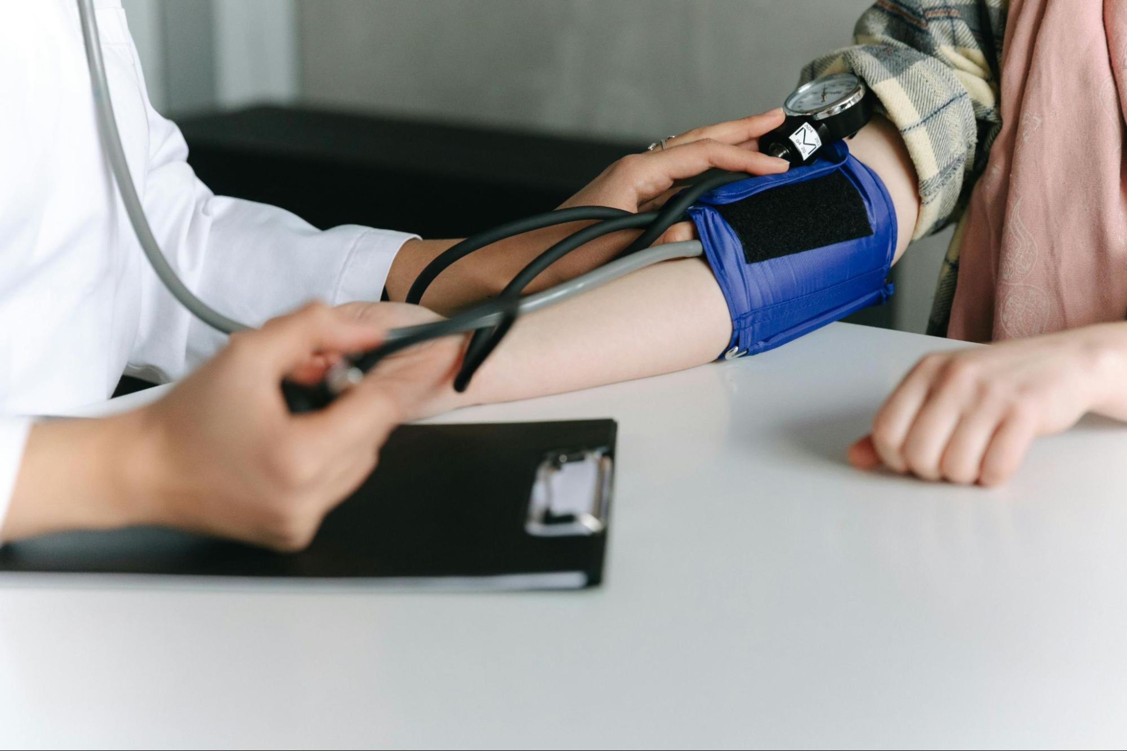 Doctor takes a patient's blood pressure using a cuff.