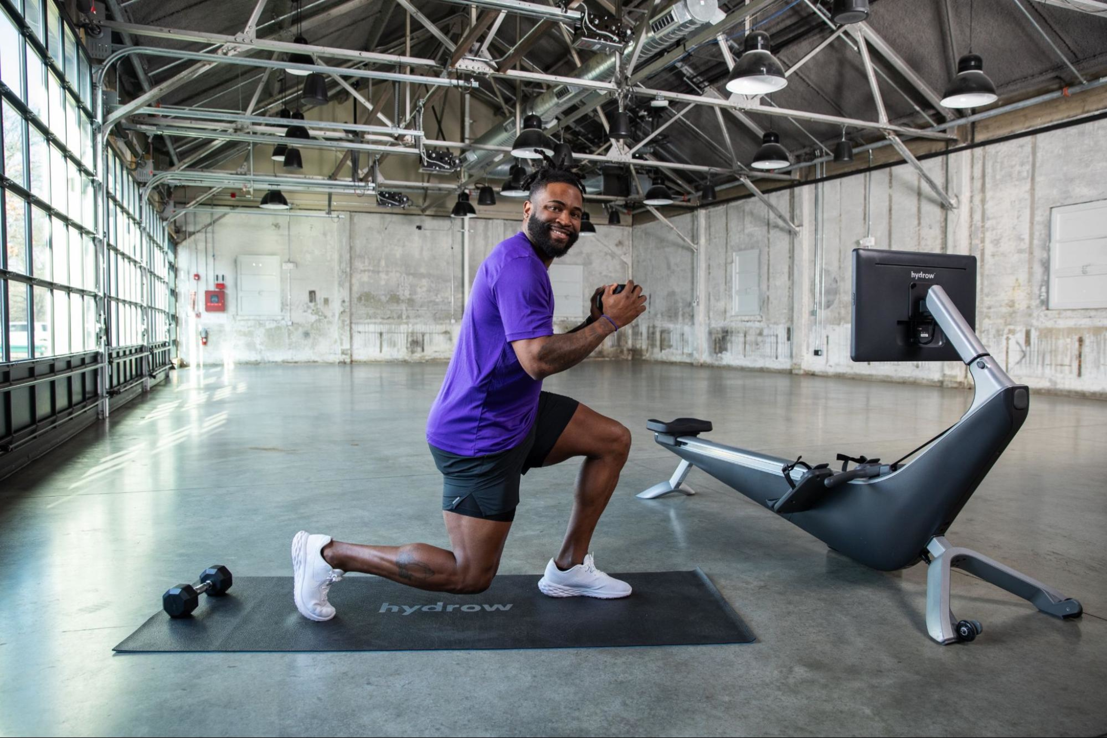 Hydrow Athlete does lunges with a dumbbell to build bigger glute muscles.