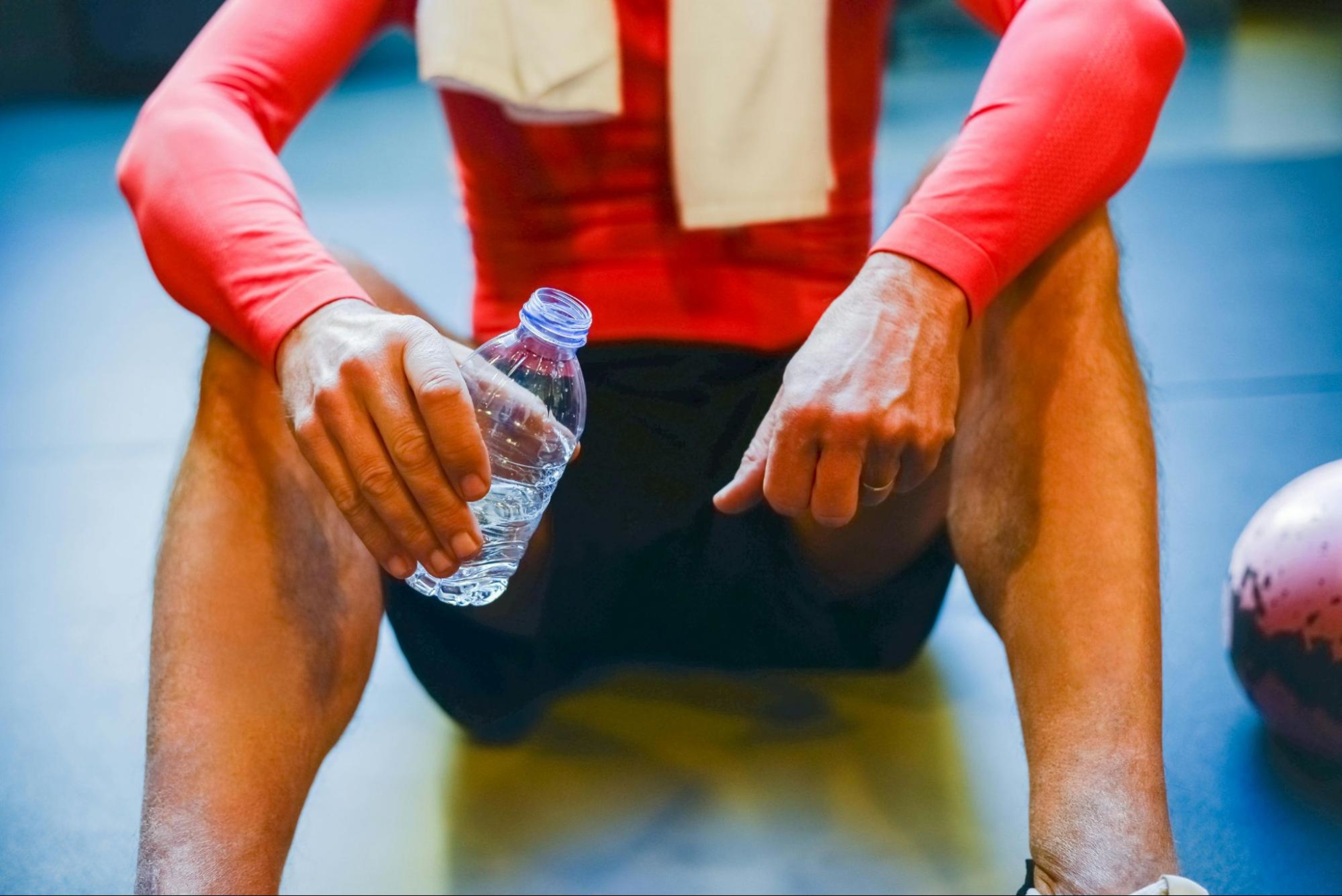 Man drinks water and rests after a glute workout.
