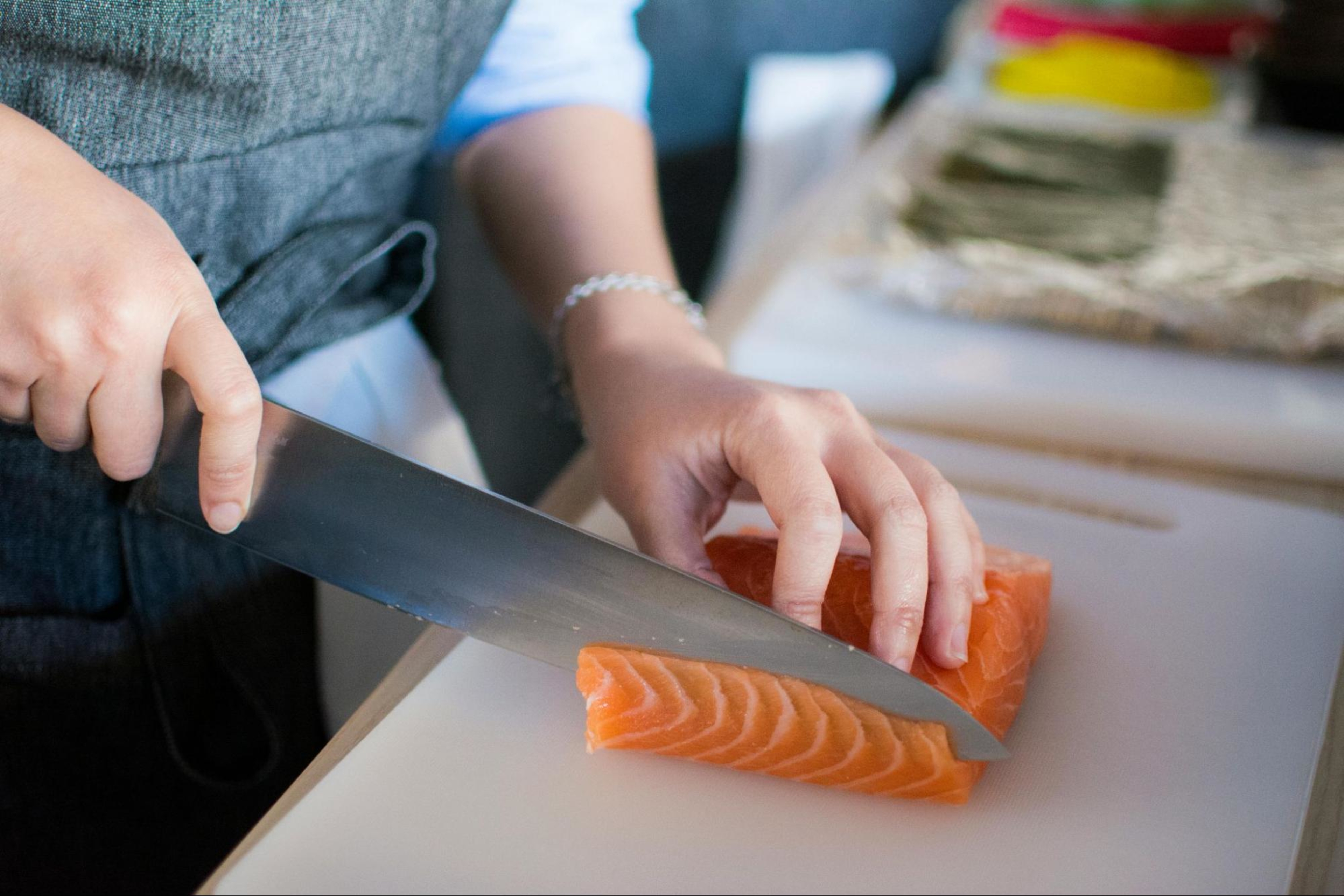 Woman looking to build muscle with protein slices up salmon with a knife.